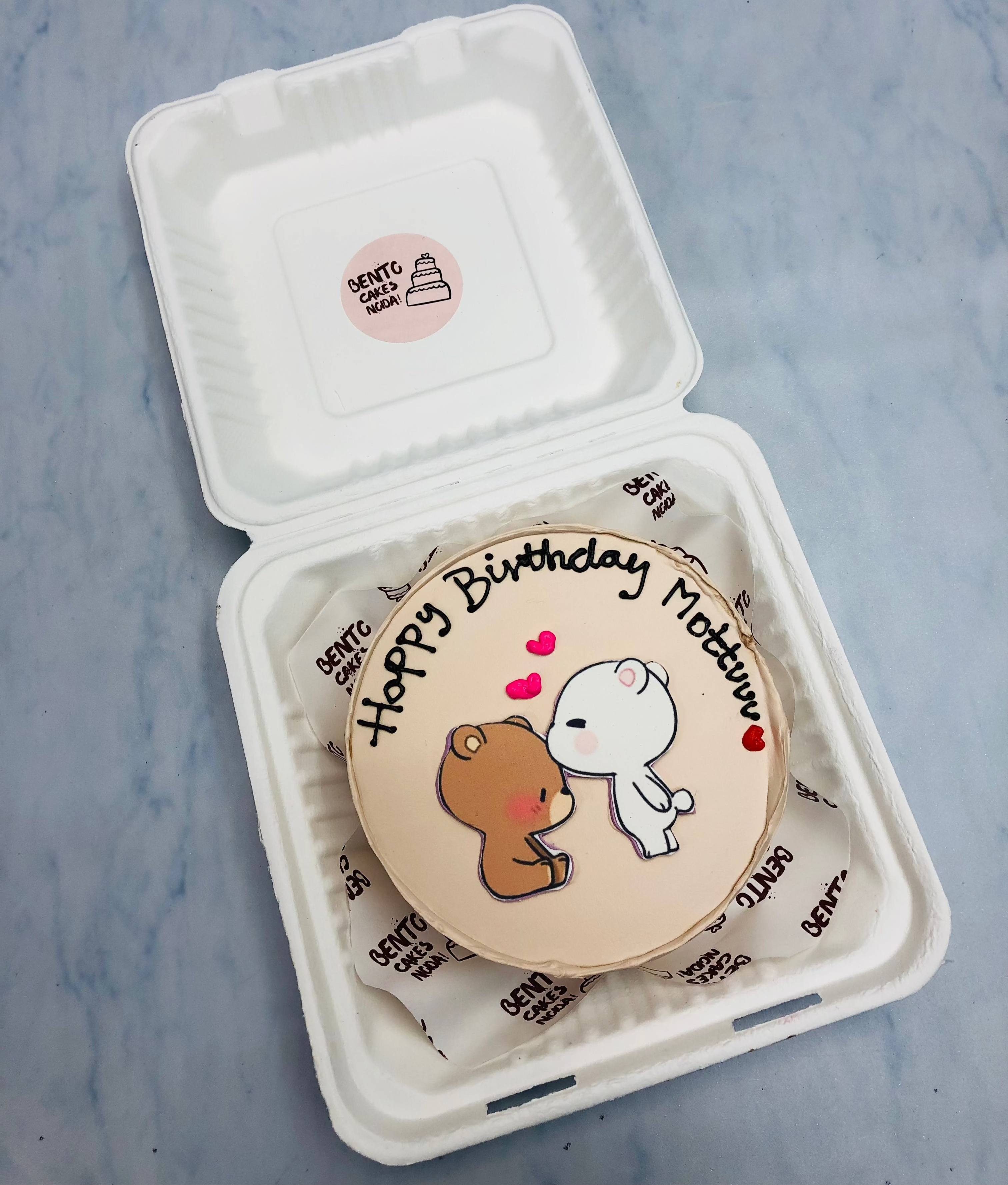 A peach color bento cake having kissing bubu dudu.