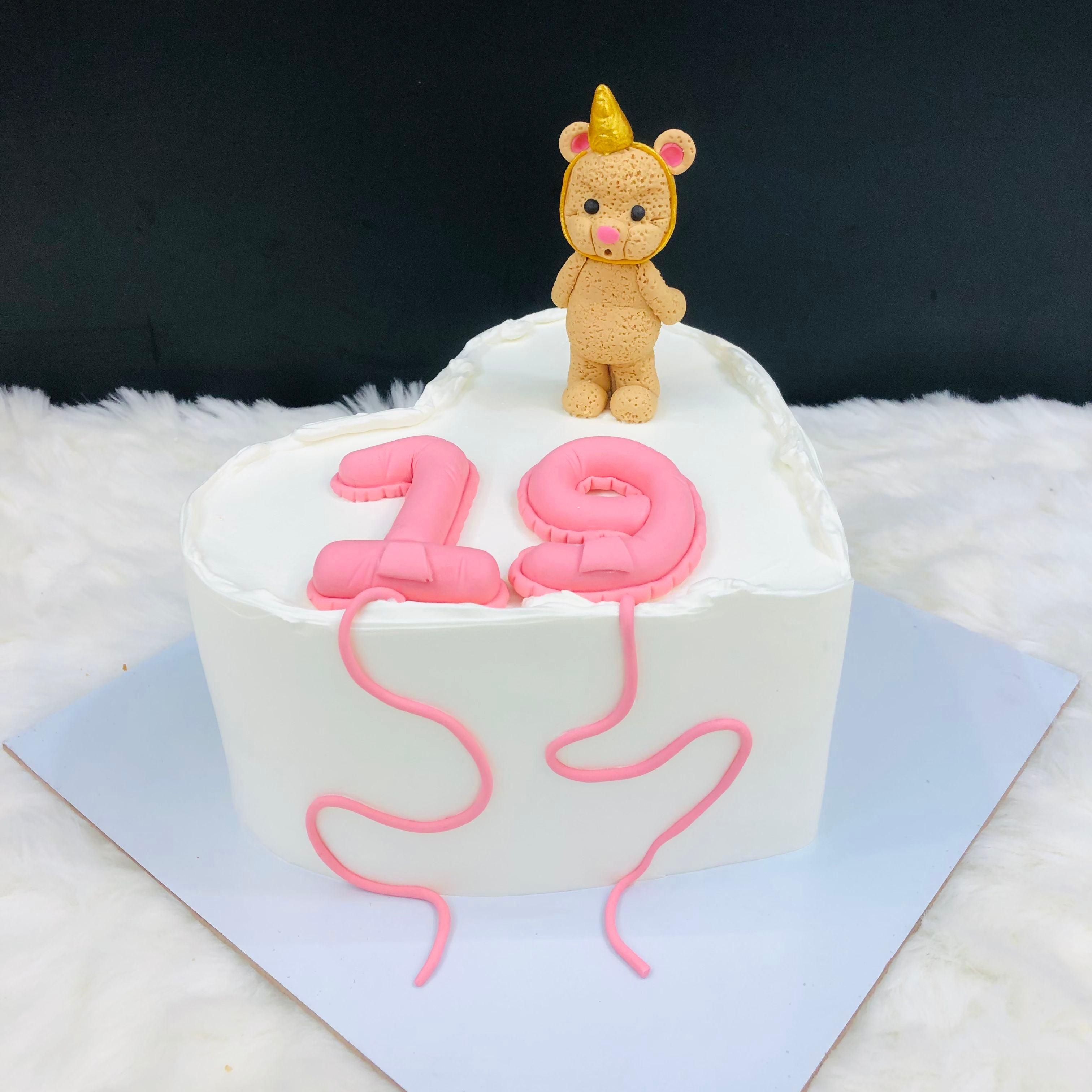 A delightful cake adorned with a cute teddy bear sitting on top, perfect for a child's celebration.