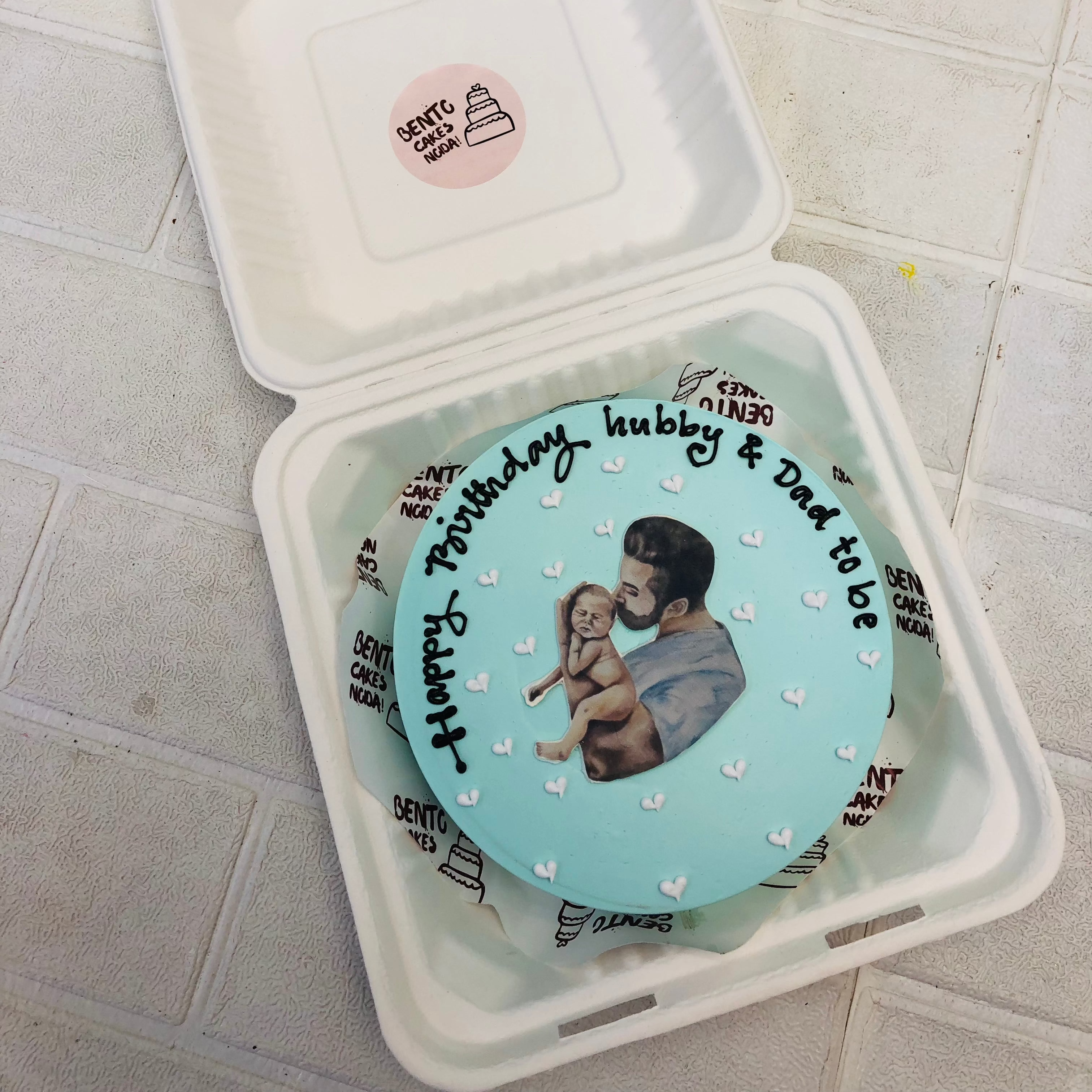 A cute cake in sky blue color with father and baby print.