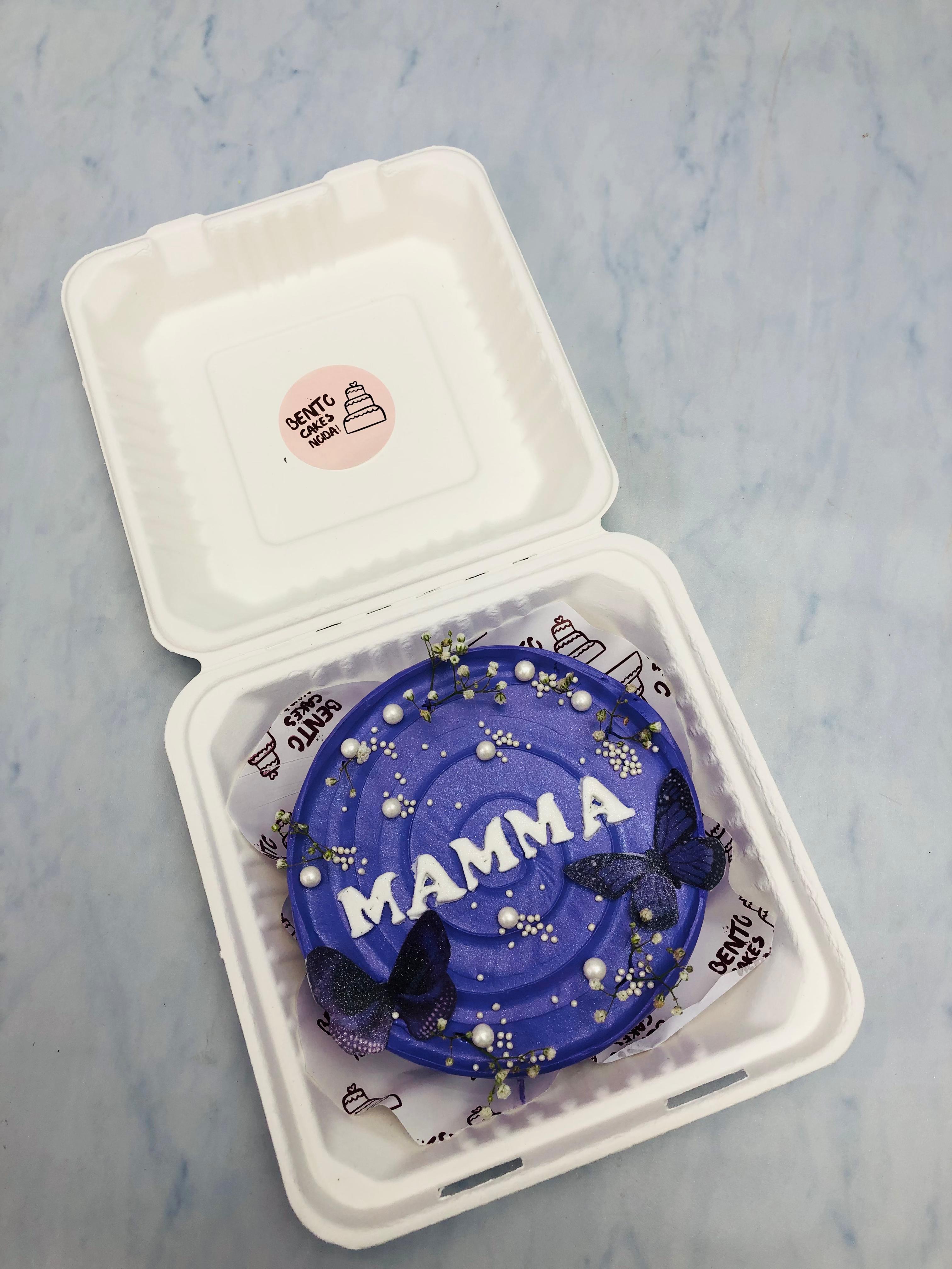 A dark purple icing cake is designed with purple butterflies and vintage florals on it.