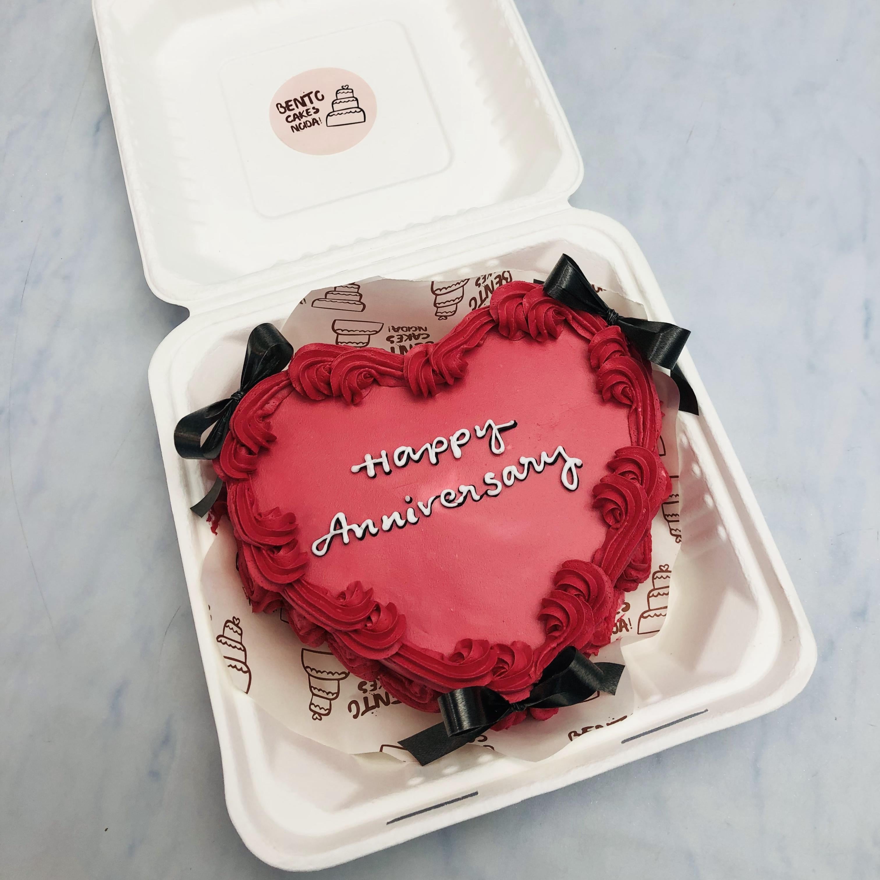 A Dark Red Heart Shape Anniversary in A bento box with black bows on it.