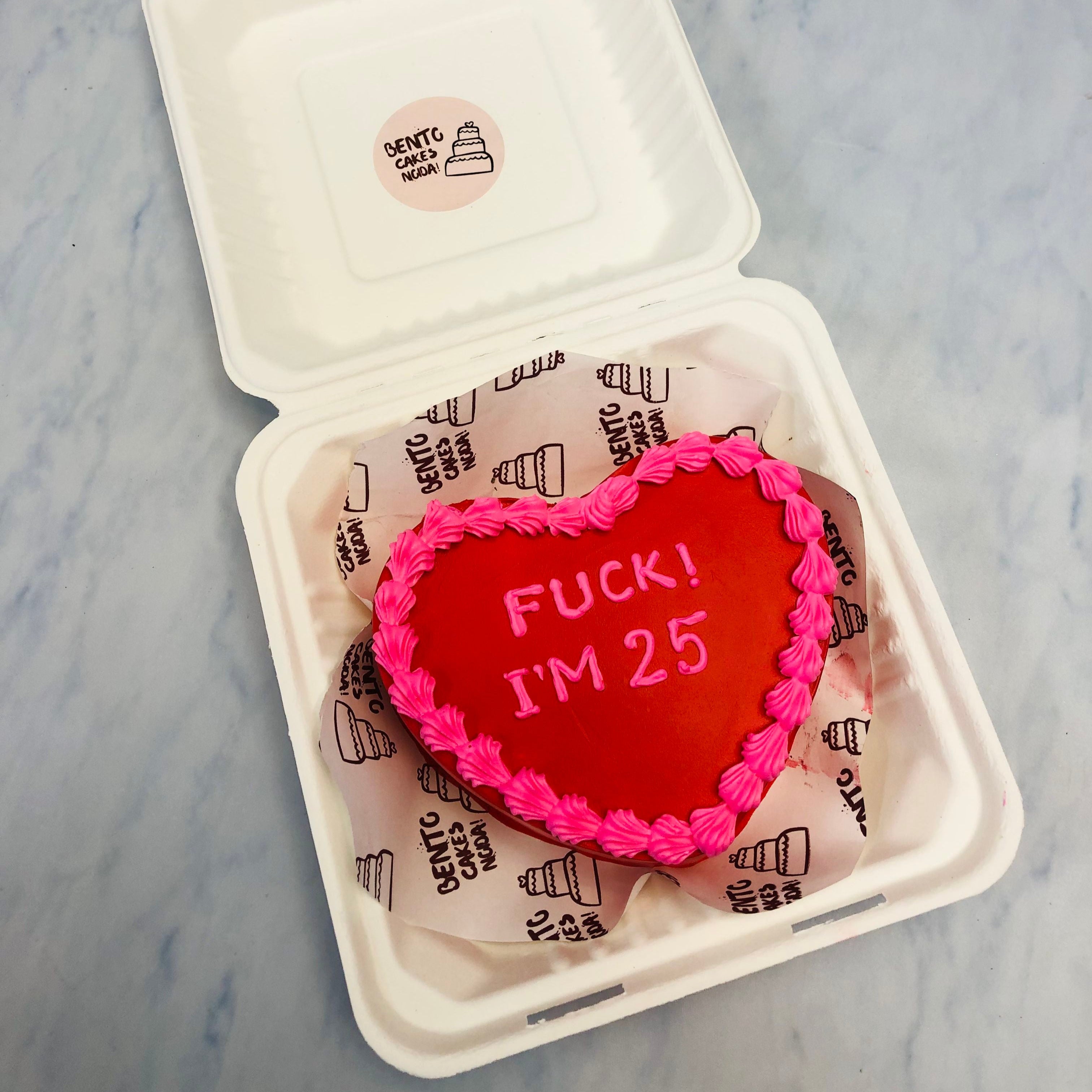 A dark red heart shape cake with pink floral design on it's border and a text written with pinkicing.