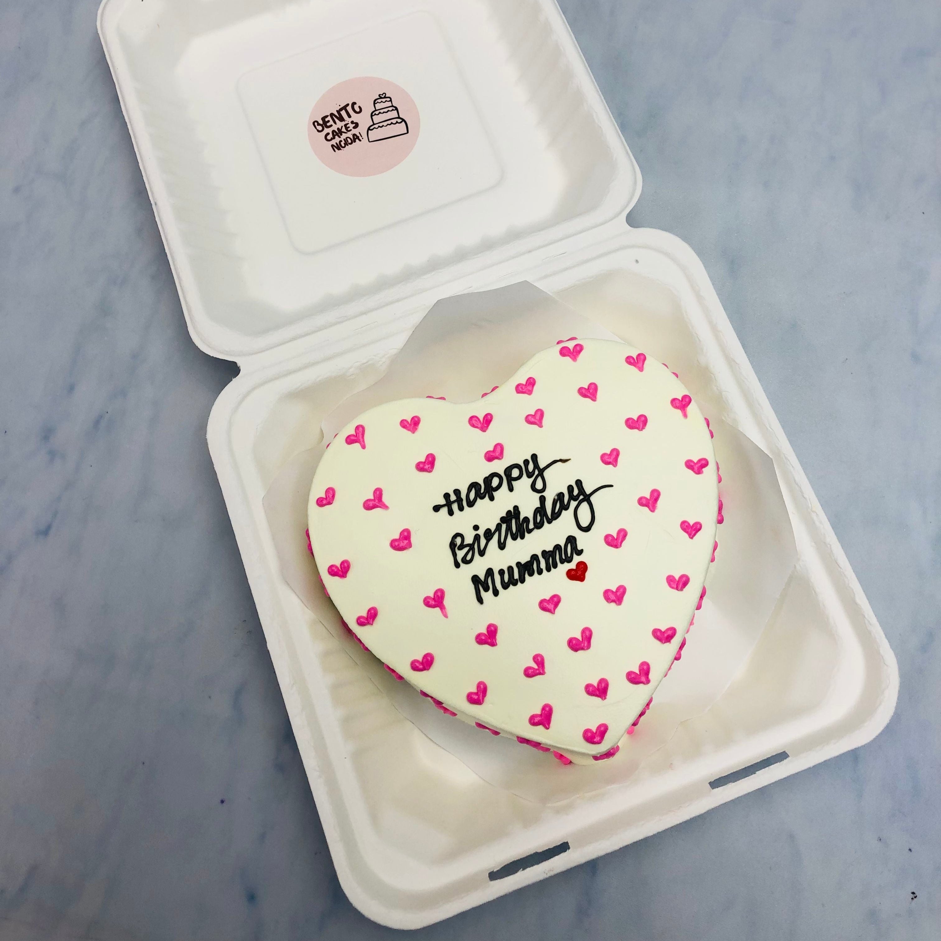 A white cake filled with pretty pink heart designes all over it.