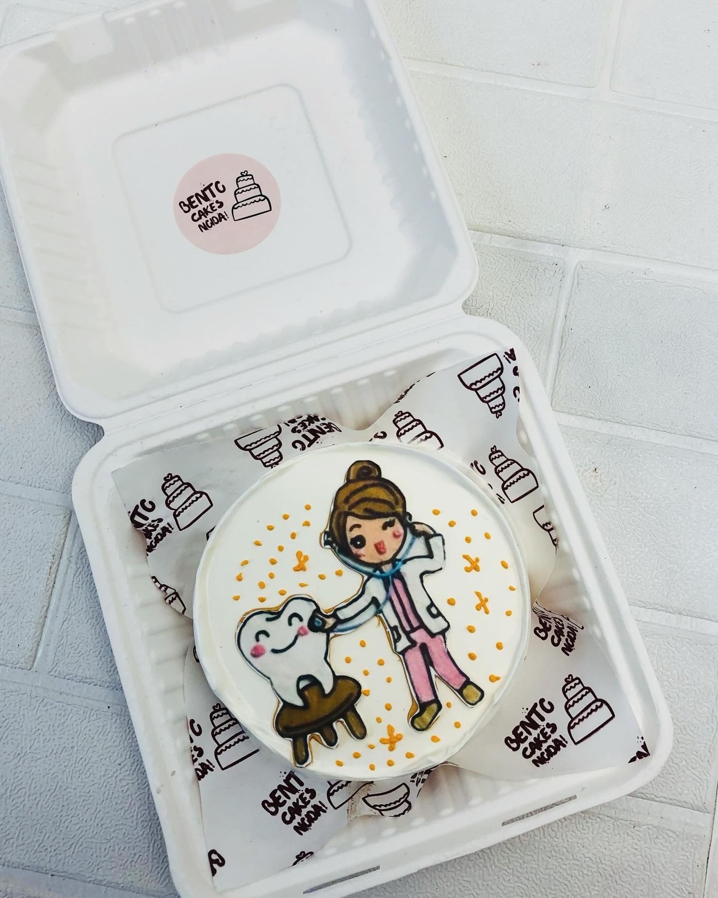 A white bento cake is designed for a dentist girl with a girl doctor and teeth print.
