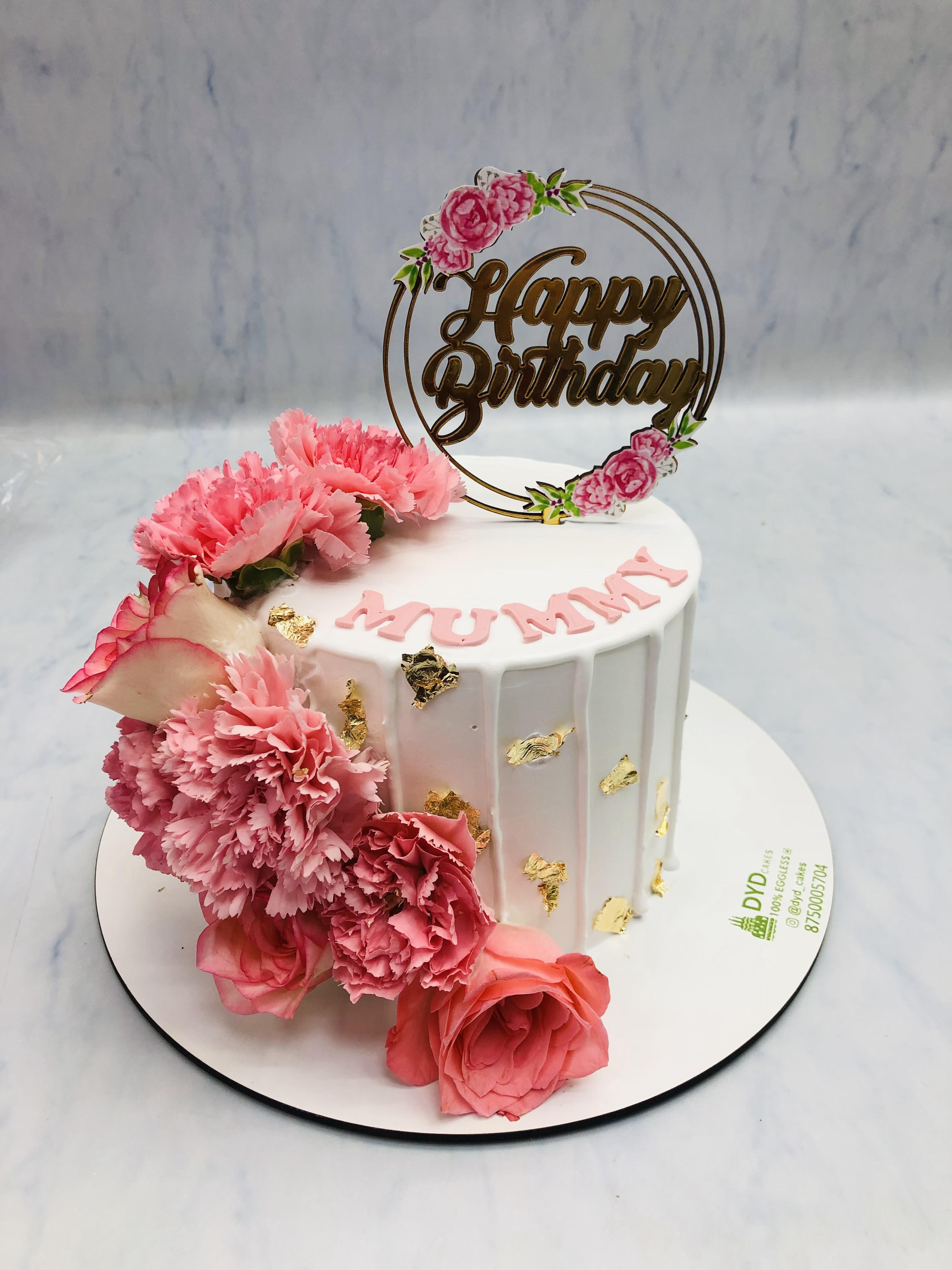 A whiten cake adorned with delicate pink roses on its top, showcasing an elegant and charming dessert presentation for birthday celebration.