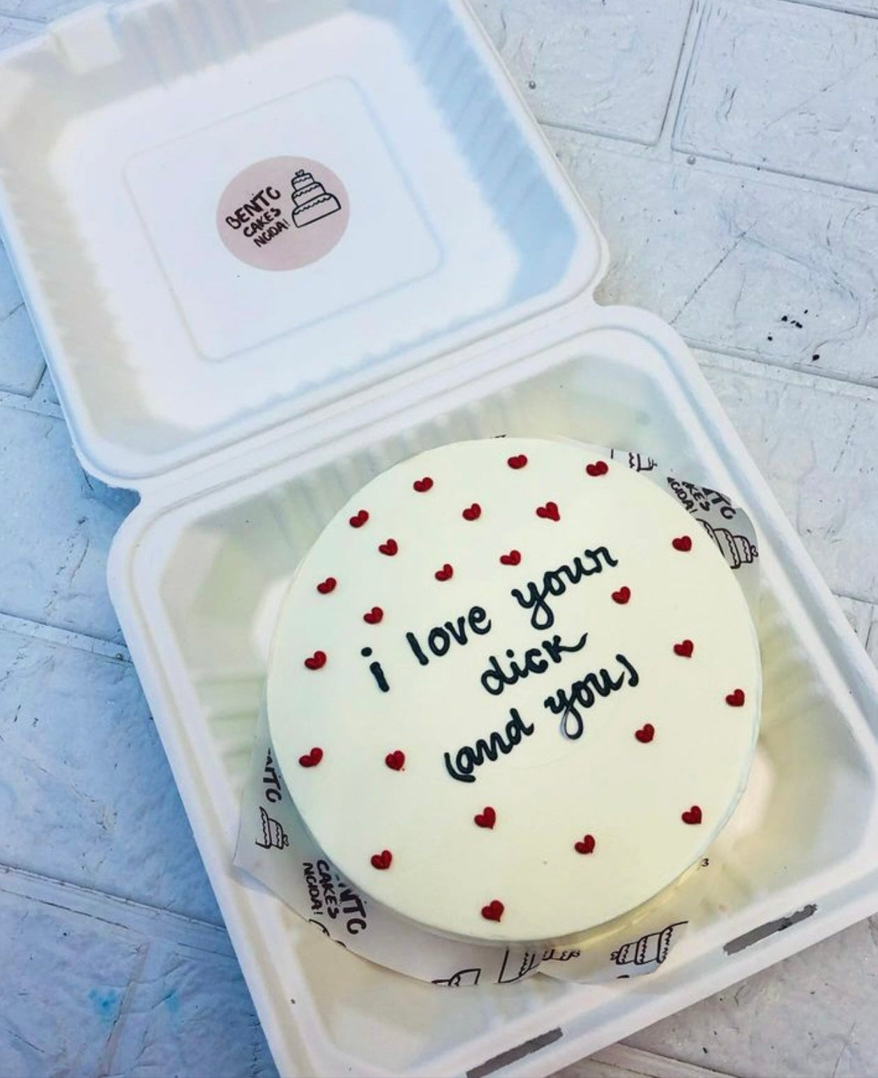 A white bento cake with pretty red hearts design and some bachelor text on it.