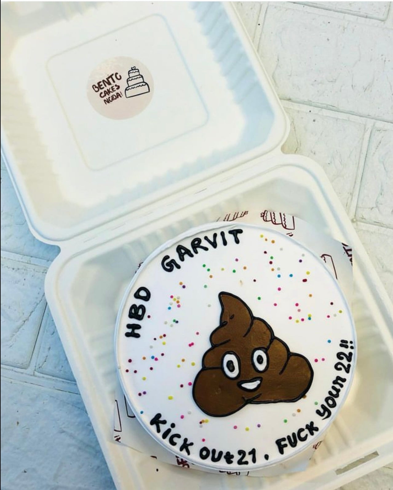 A white bento cake is designed with shit theme on cake for 22 birthday.
