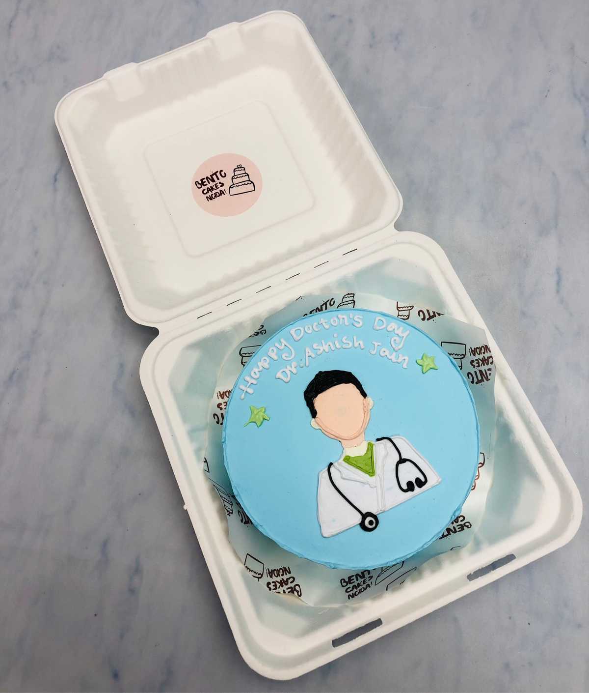 A light blue bento cake for a doctors birthday with a doctor in dress.