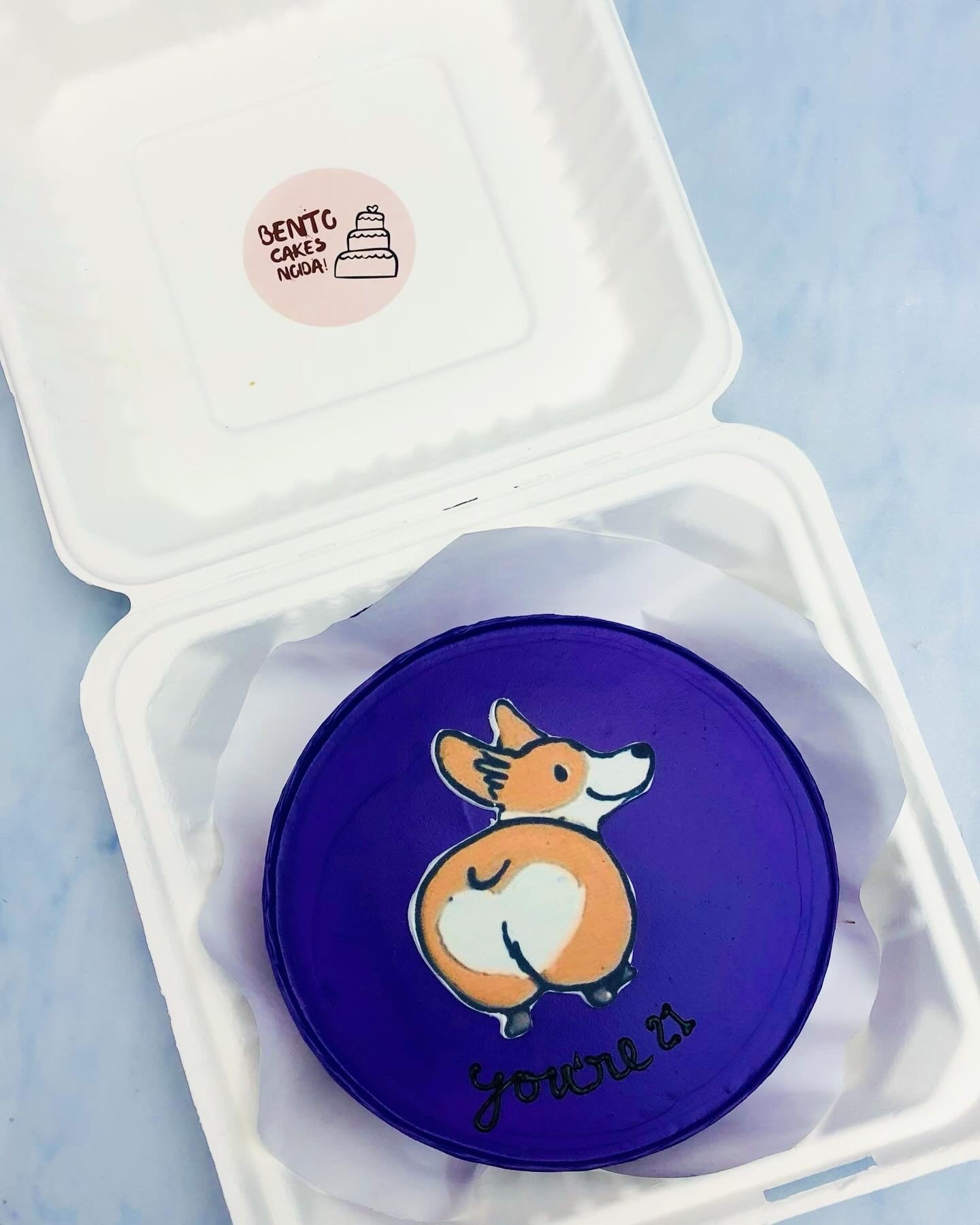 A dark blue bento cake showing a dog print for 21 birthday.