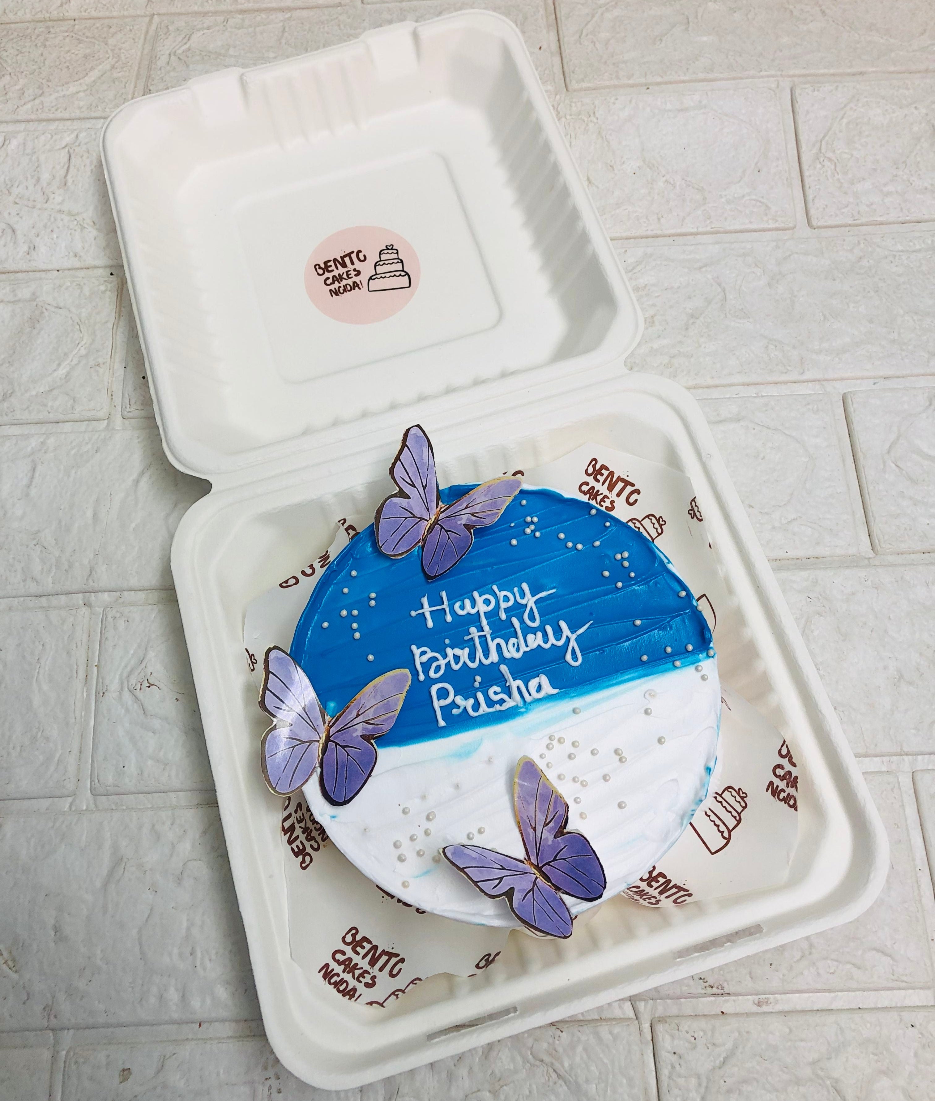 A blue half shades on bento cake decorated with purple butterflies for birthday.