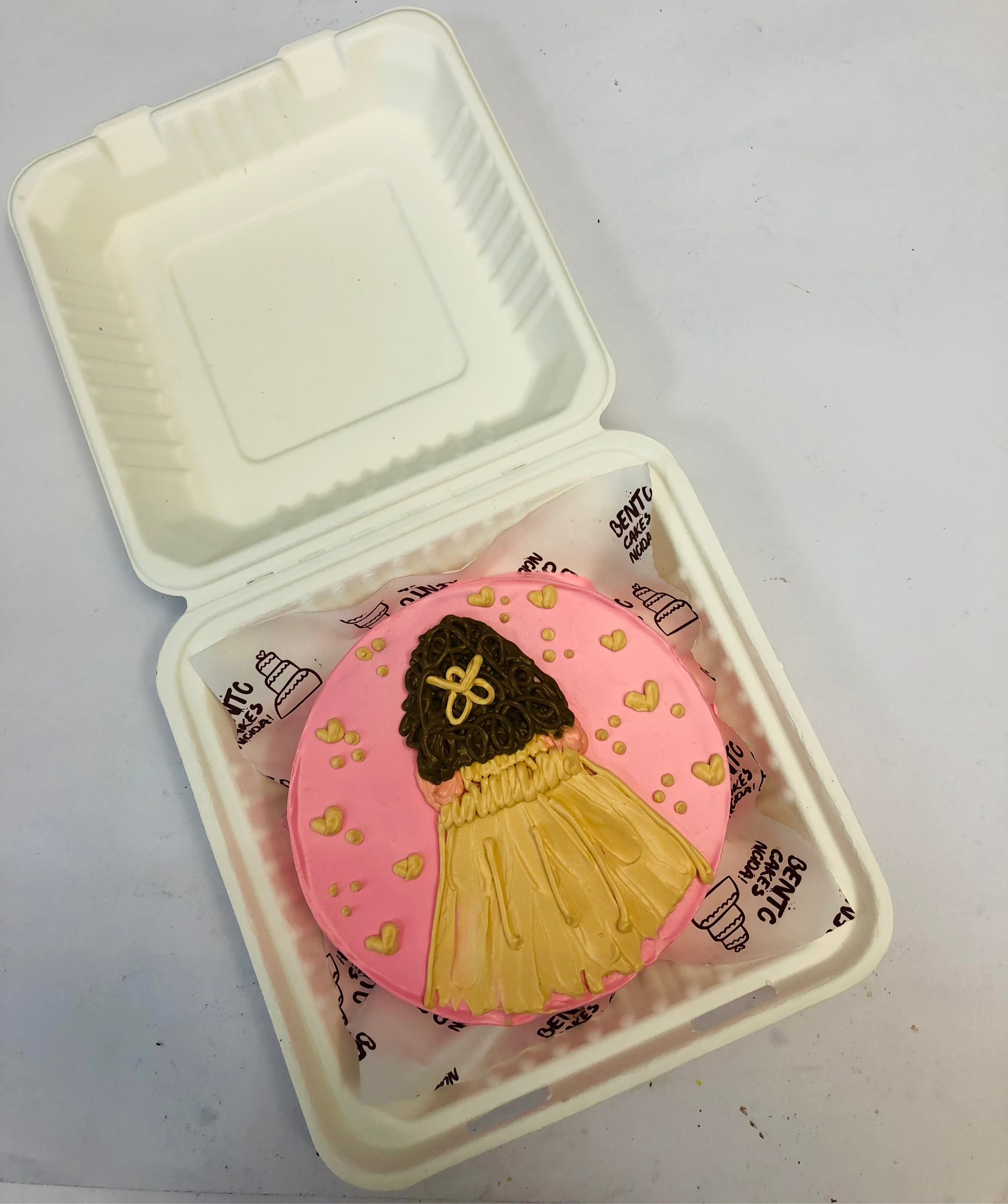 A beautifully crafted decorative cookie featuring a pink icing base with a delicate dress design.
