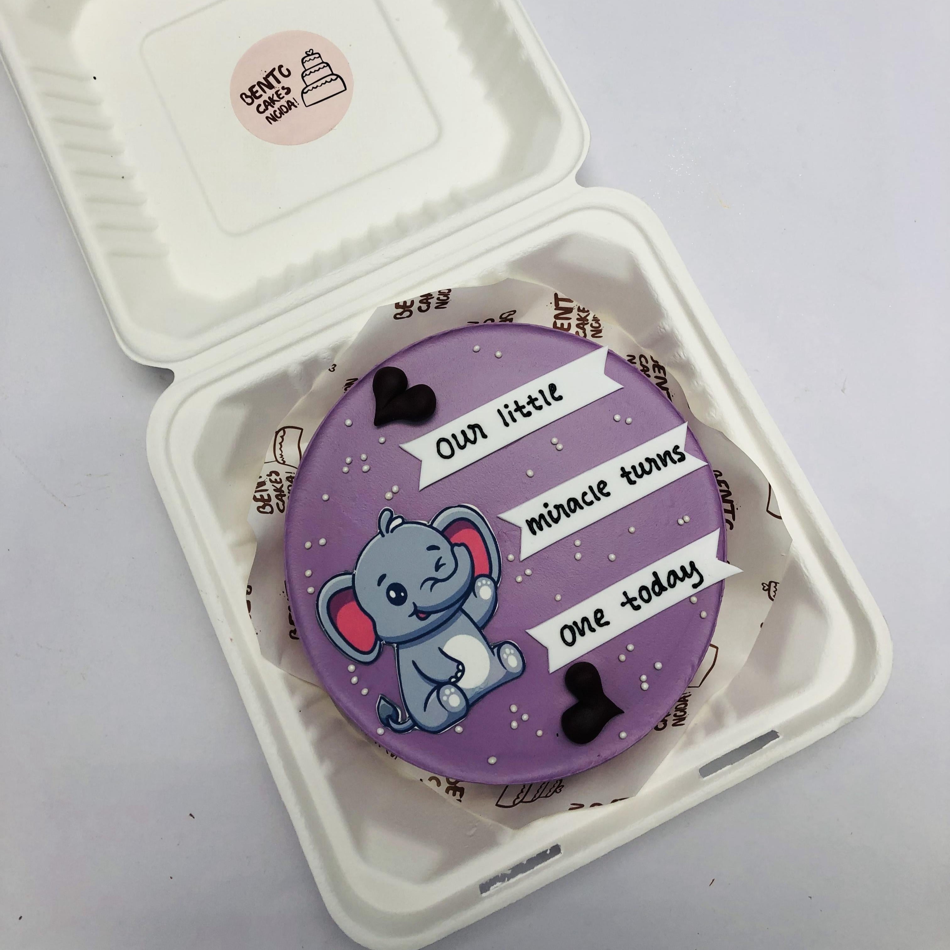 A purple bento cake with cute elephant print and black hearts.