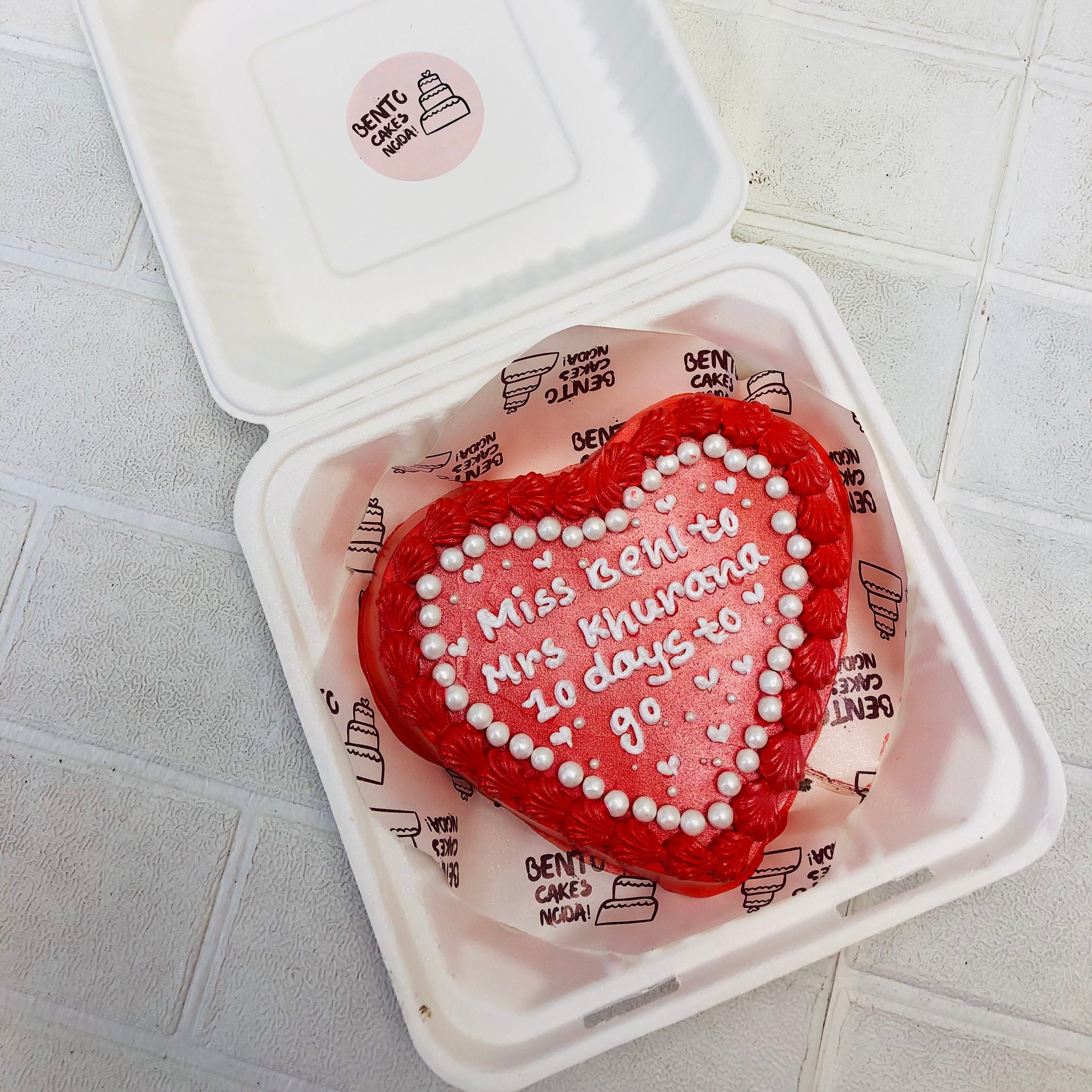 An Engagement Theme Red Heart Bento Cake designed with white sprinkles and a loving text written on it.