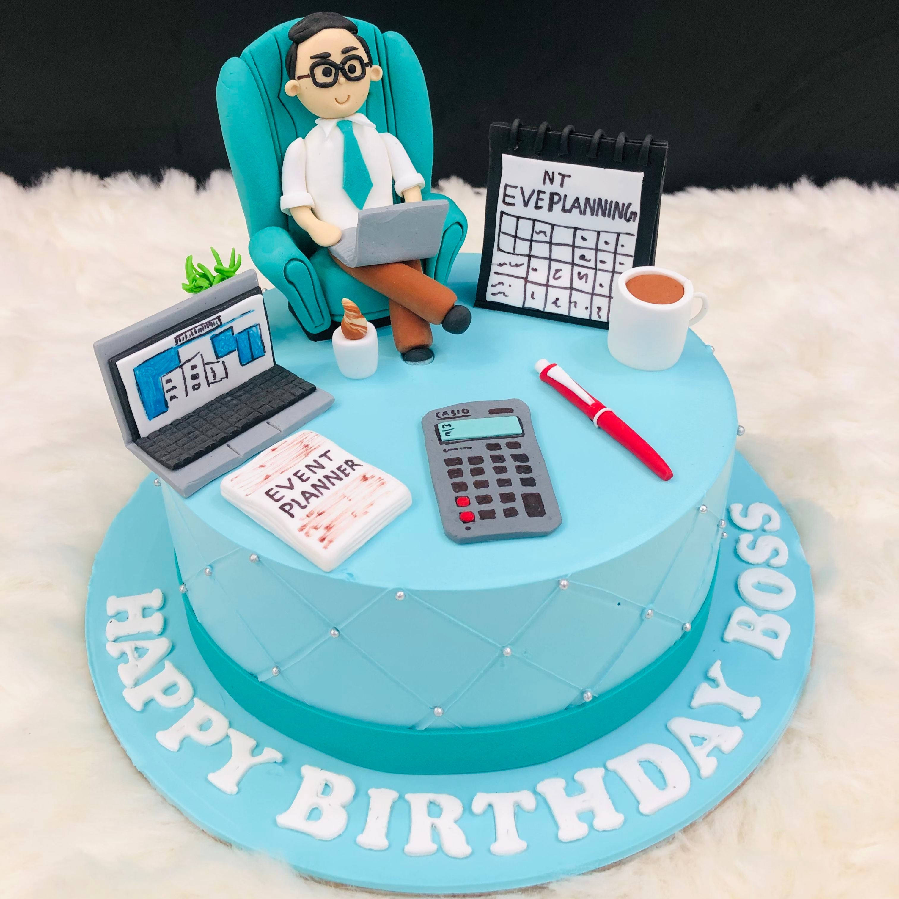 A birthday cake is displayed while a man sits in a chair, using a calculator to tally up the celebration's expenses.