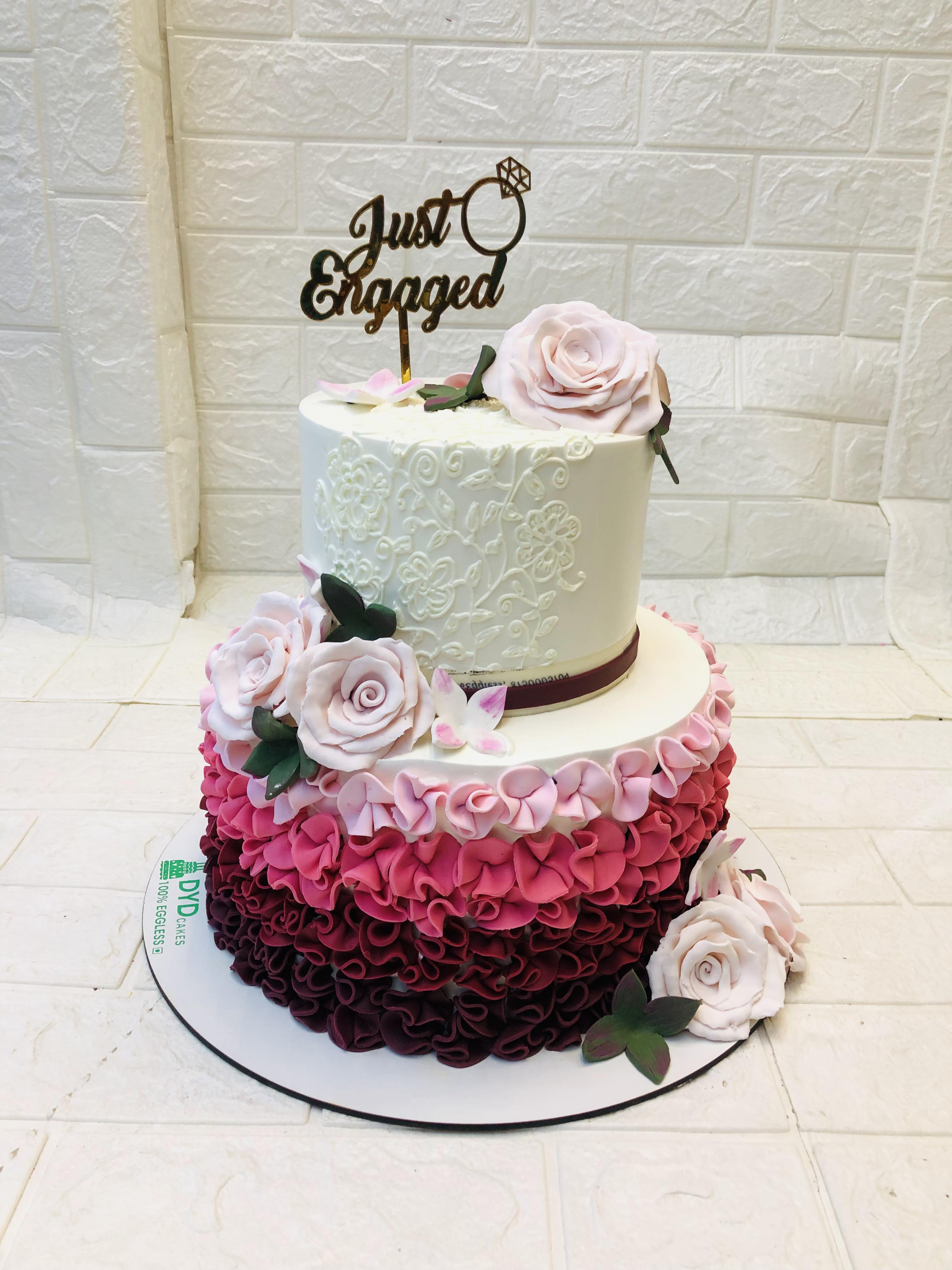 A 2 tier floral design engagement cake decorated with fondant pink roses.
