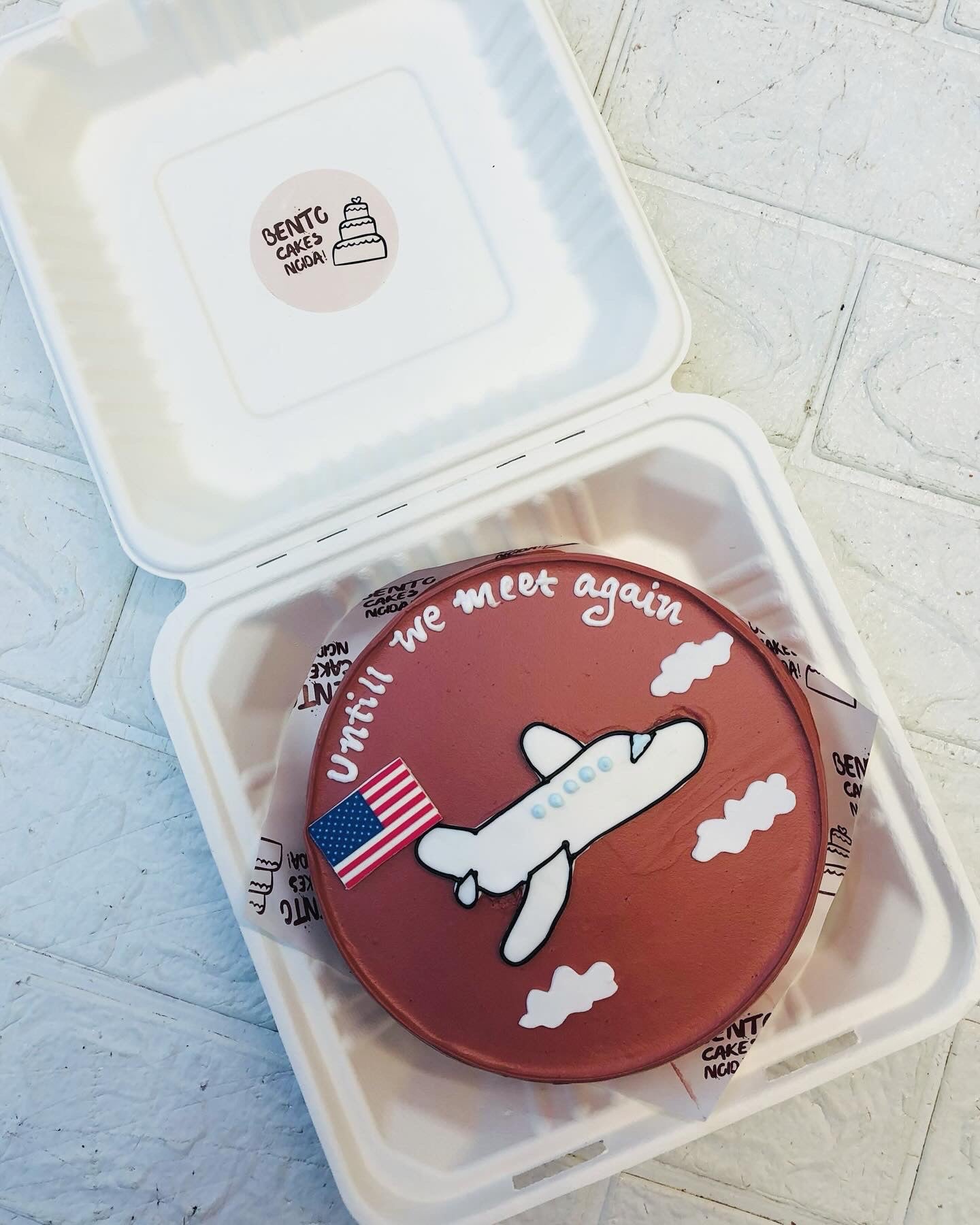 A brown bento cake with an american flag and a flight design for farewell.