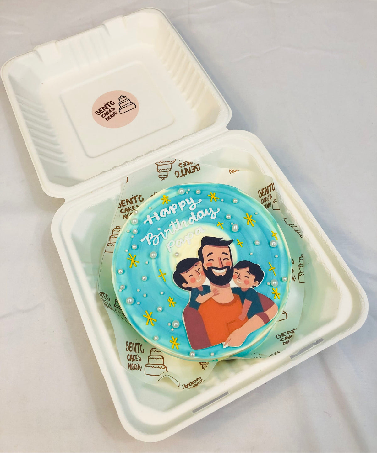 Aesthetic blue ombry design cake having a father with 2 childs print and decorated with white sprinkles and stars.