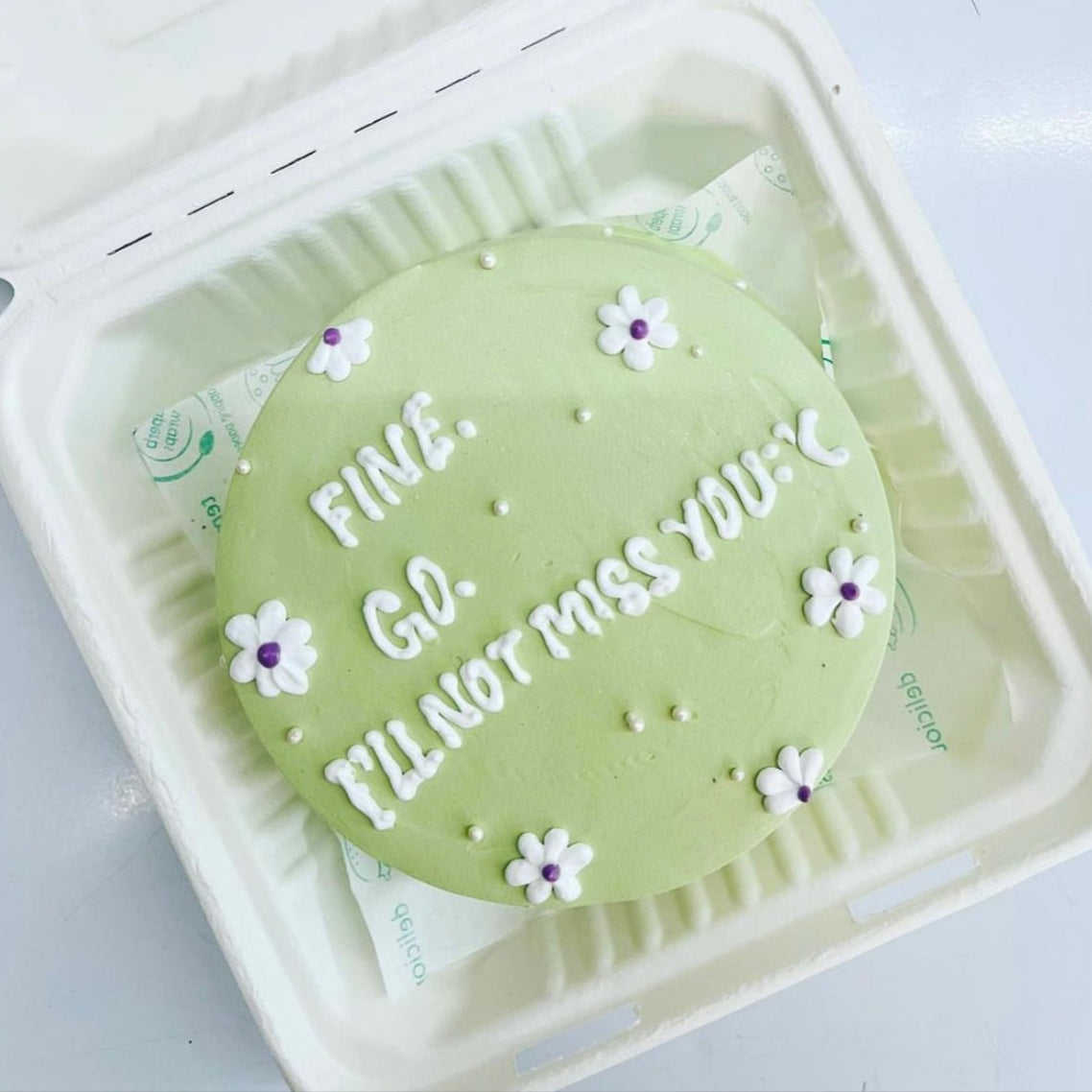 A decorated cake with the inscription "Fine go I'll not miss you" prominently displayed for a birthday celebration.