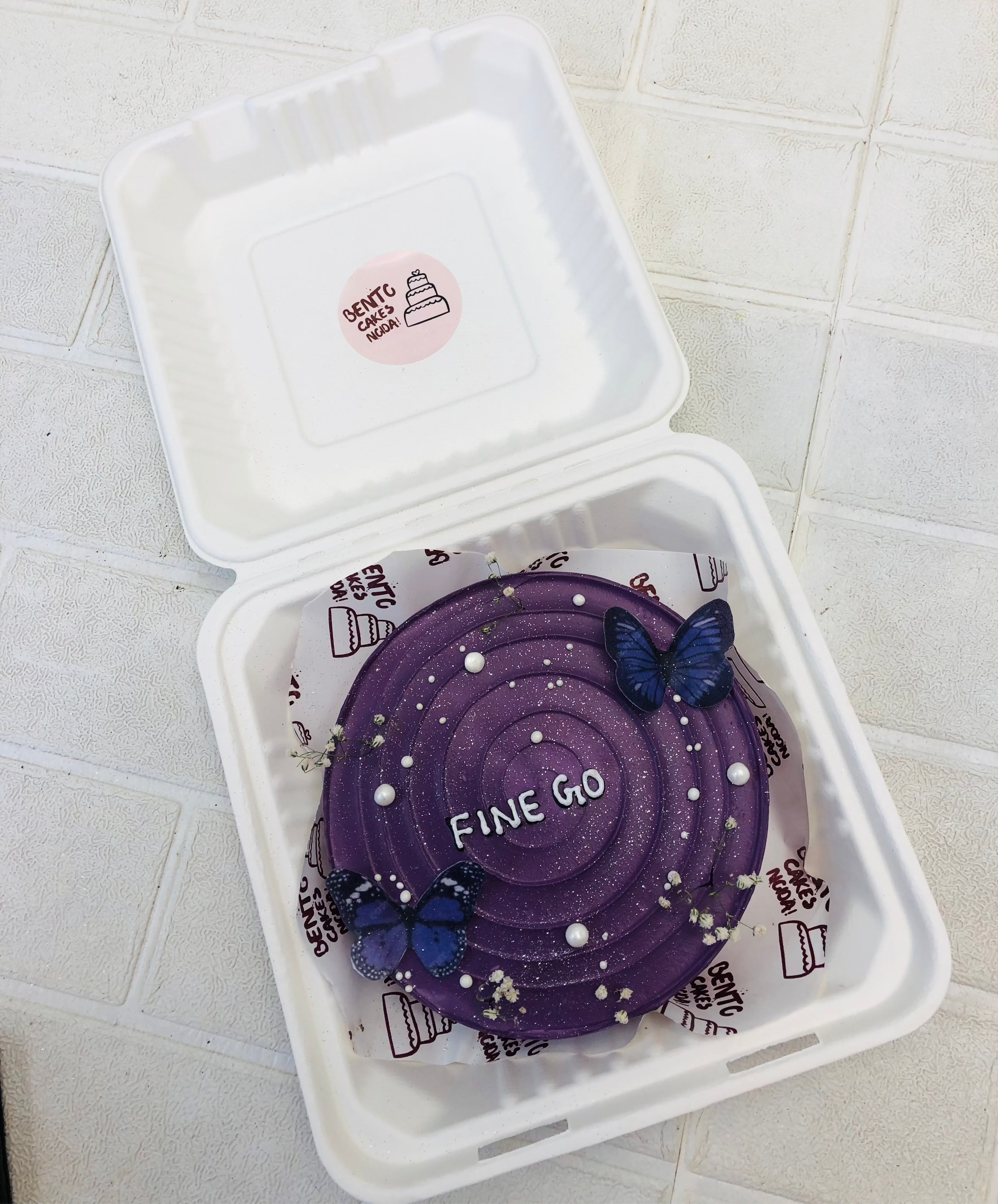 A dark purple bento cake having decorative butterflies and is designed for farewell.