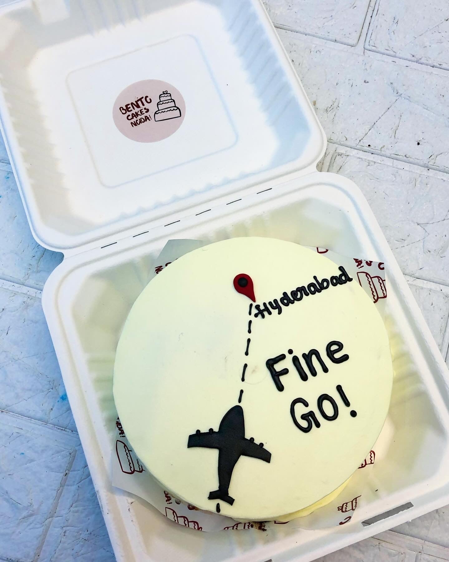 A white bento cake is designed on a flight to Hyderabad with safe journey text.