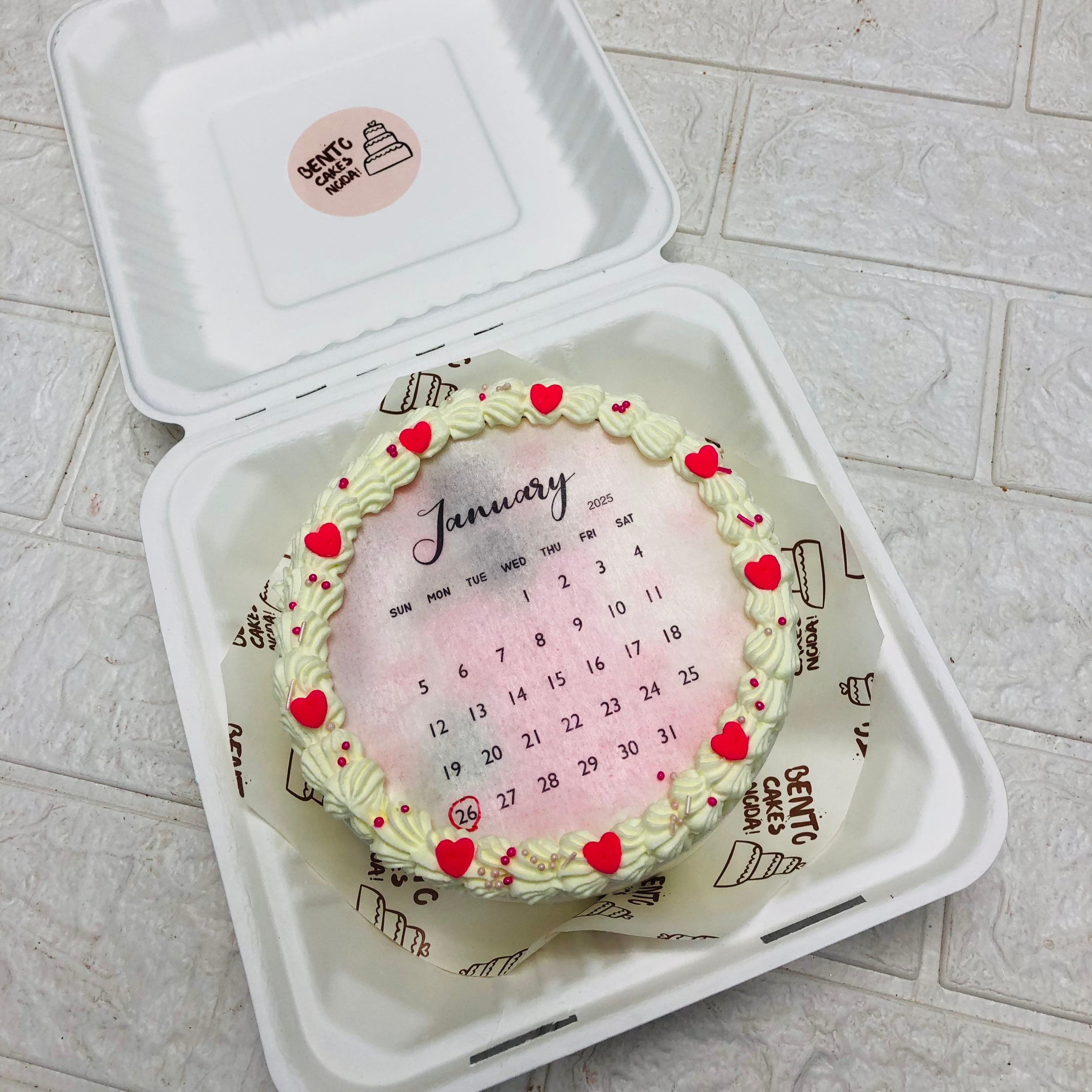 A calendar-themed cake elegantly displayed in a box, situated on a polished table surface.