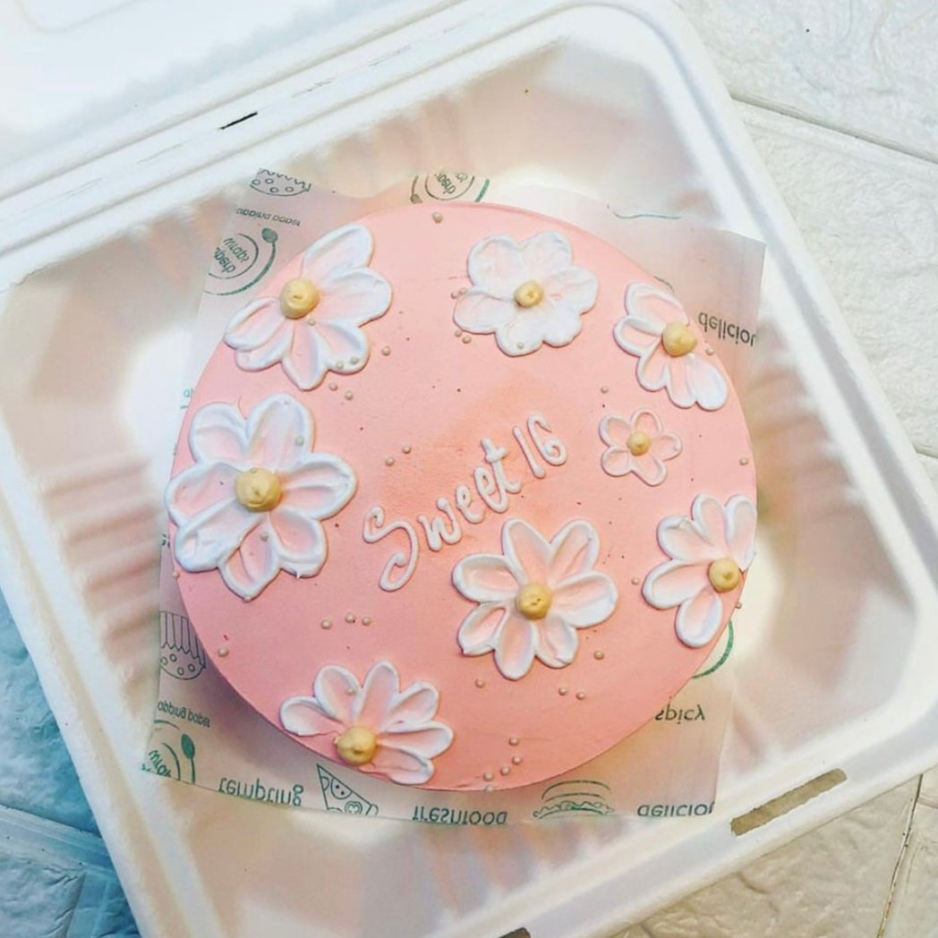 A beautifully decorated cake in a bento box, adorned with colorful flowers design on top.