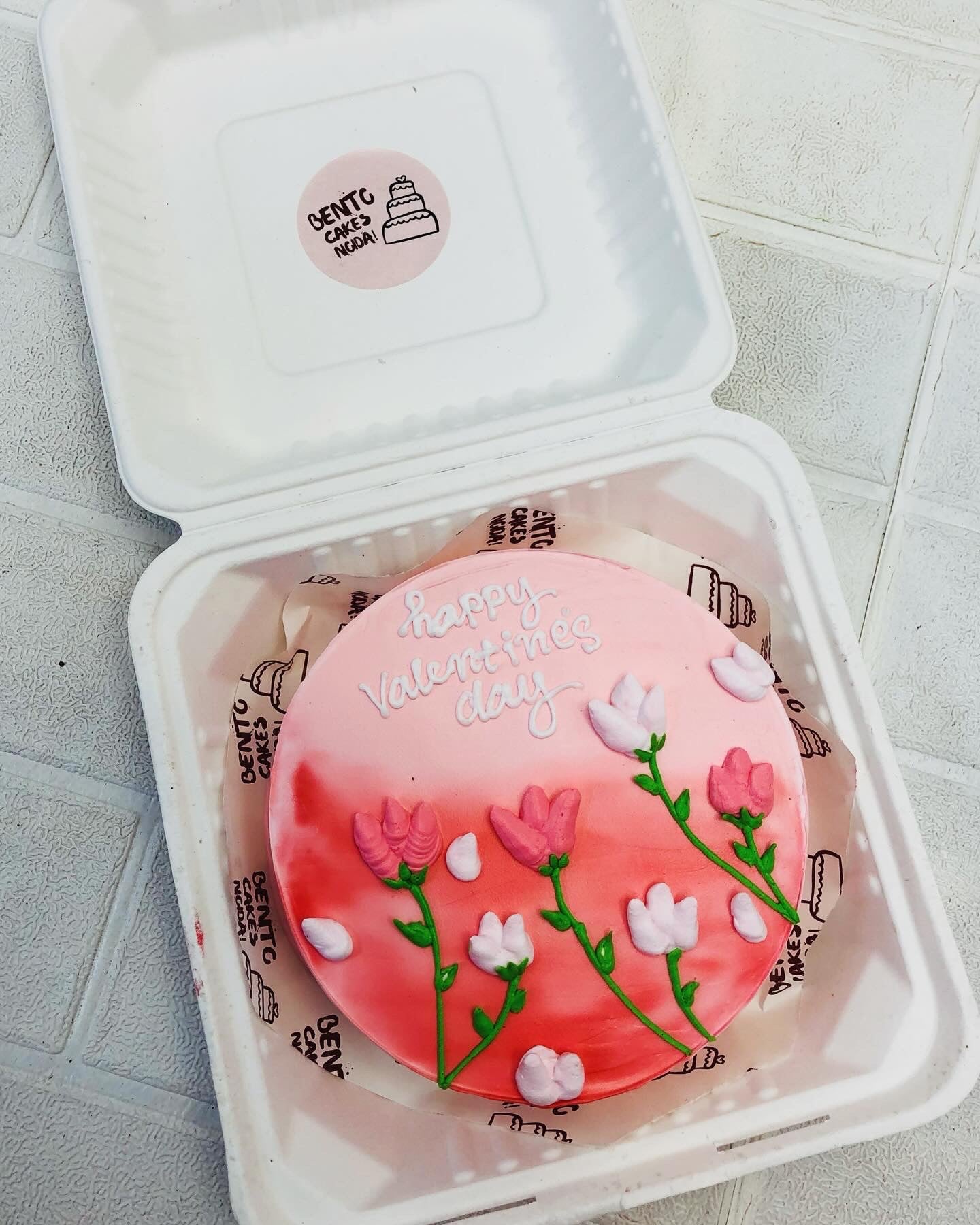 An aesthetic pink red bento cake with pink and white creamy floral design on it for Vallentines Day.