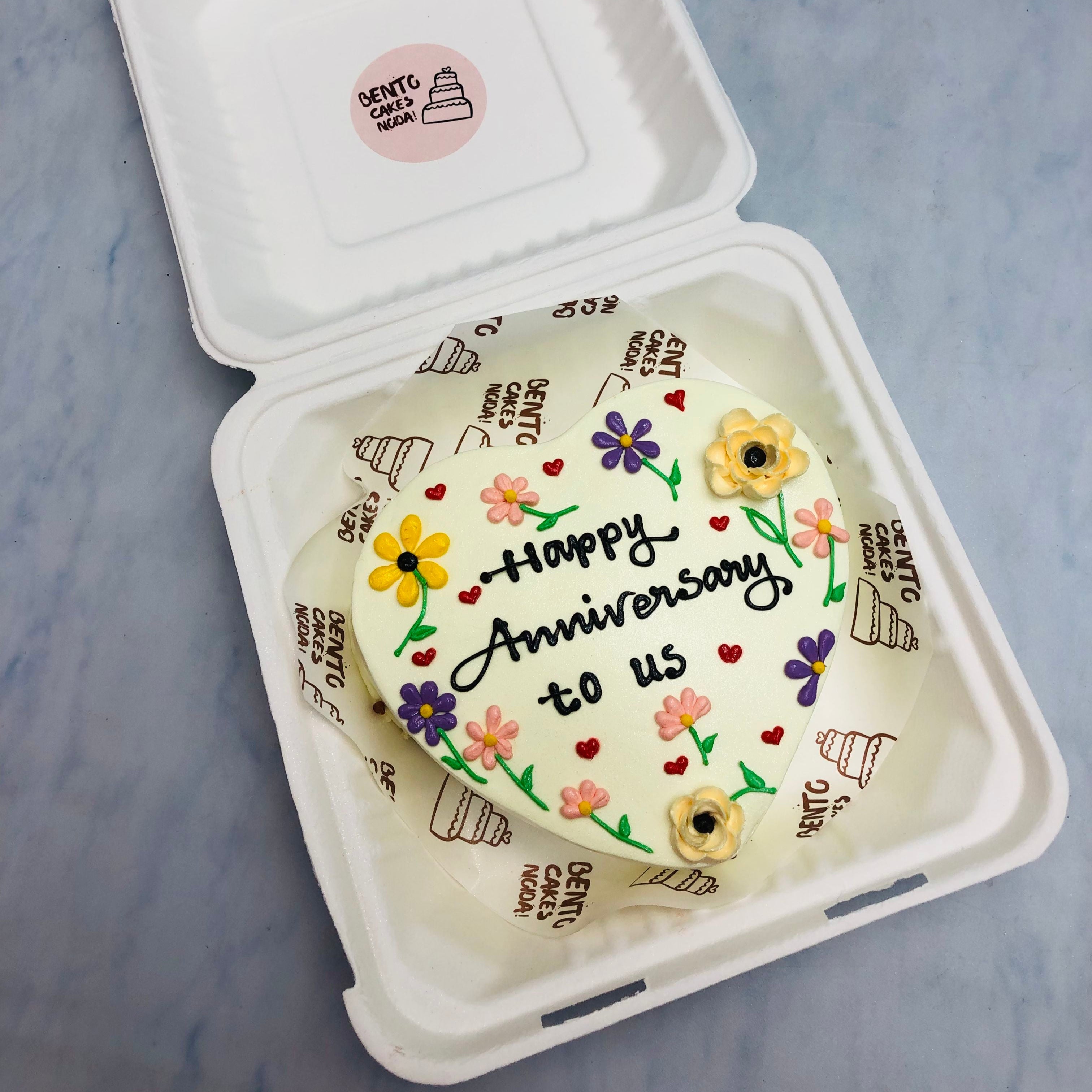 An offwhite heart shape cake with colorful florals design all over the cake and is specially desgned for anniversary occasions.