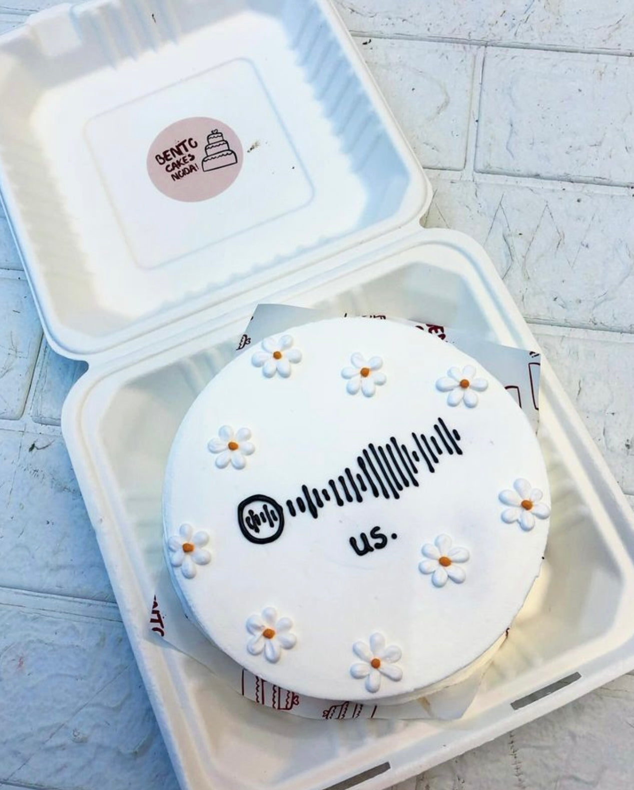 A white bento cake is designed fo music lover having white florals design and music tune design.