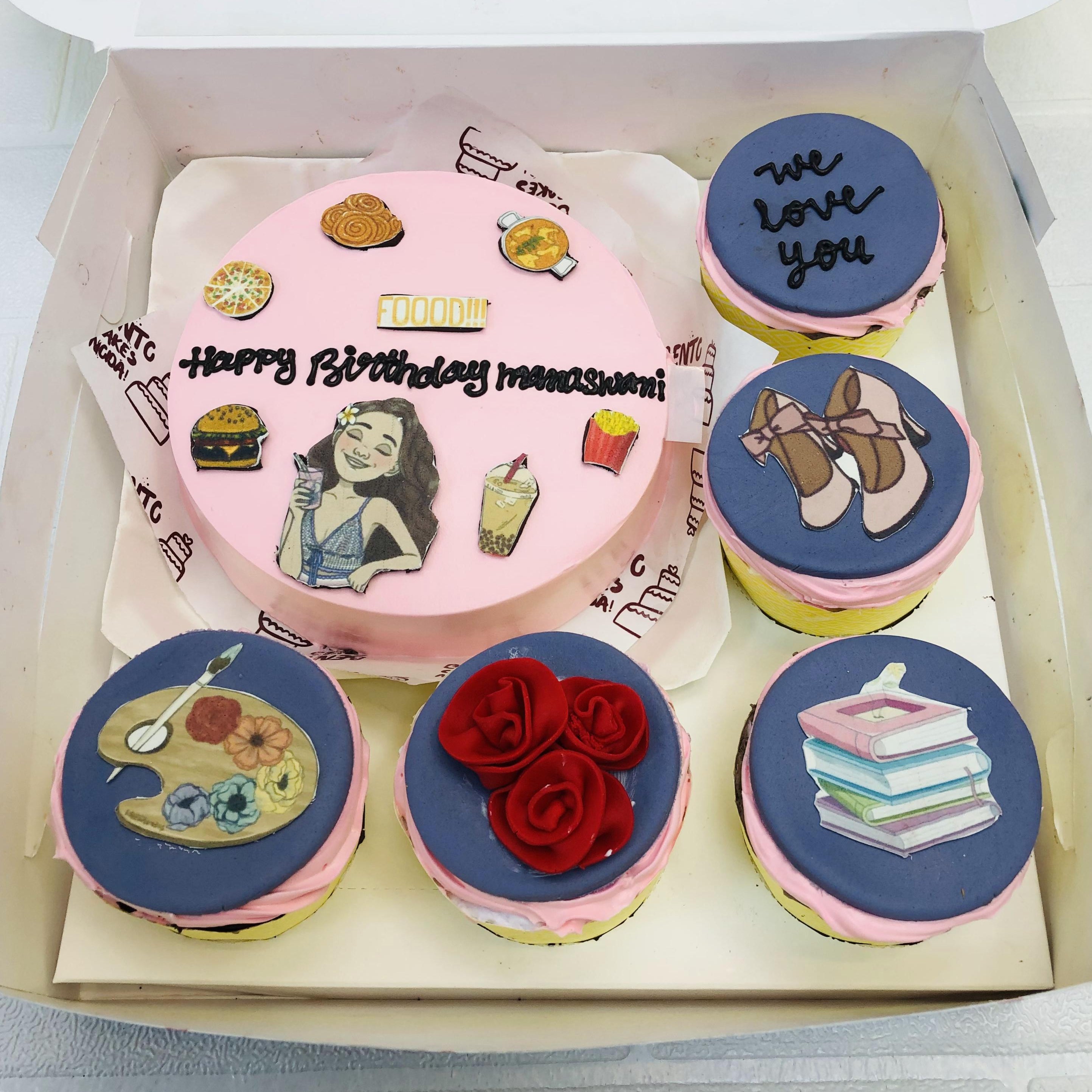 A bento combo cake set featuring a large round cake and five smaller cupcakes. The main cake has pink frosting and food-themed decorations, such as a burger, fries, and a drink, with the text "Happy Birthday [name blurred]" and "FOOOD!!!". The cupcakes display unique designs, including a palette with brushes, red roses, books, shoes, and the text "we love you".