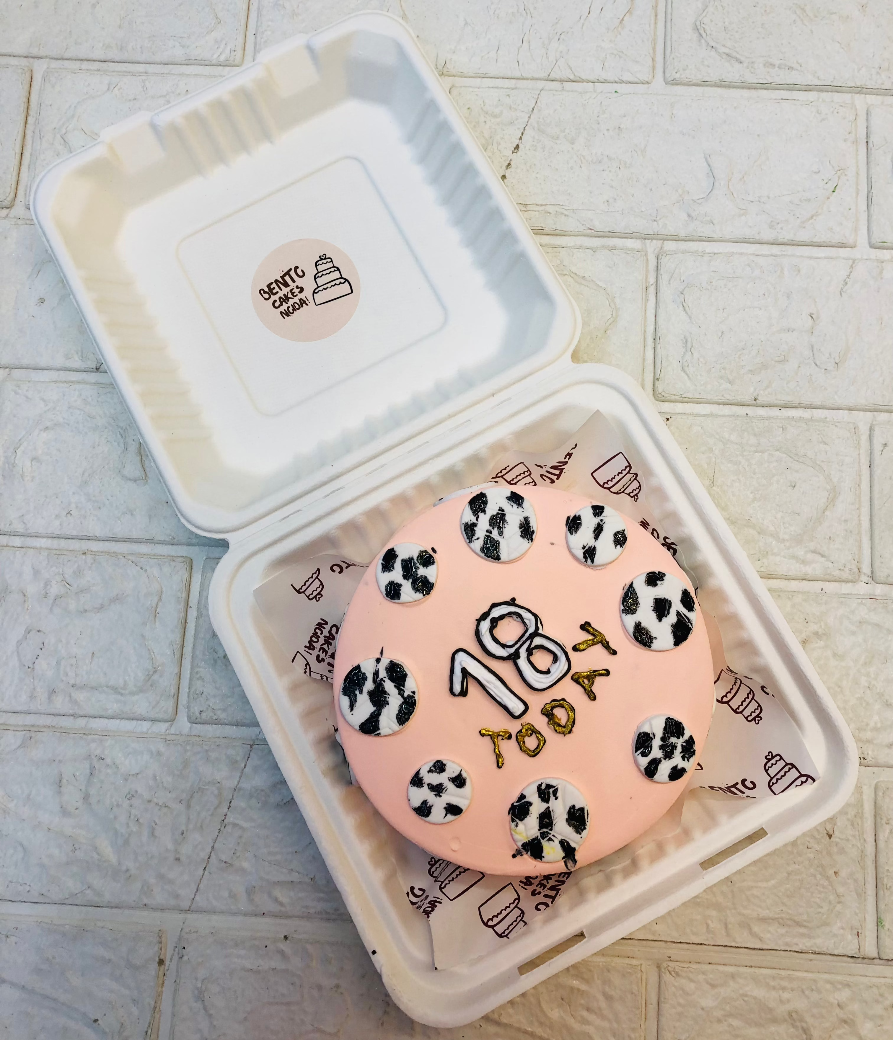 A peach color bento cake with fondant footballs design on it.
