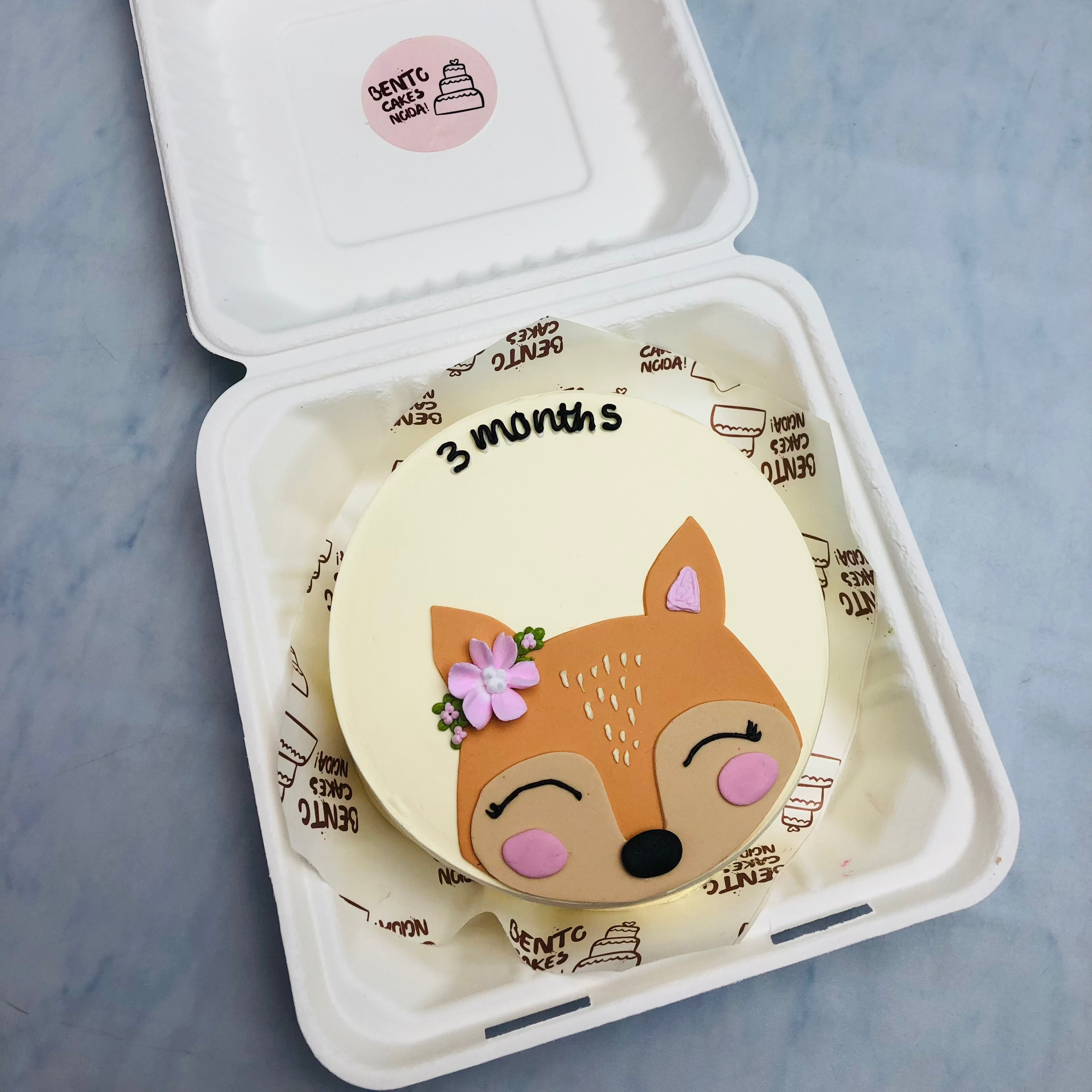 An offwhite cake with a cute fondant fox face design for a 3 months baby.
