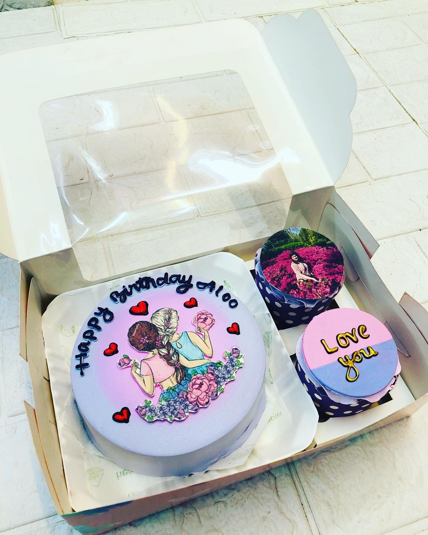 A delightful box filled with a beautifully decorated cake and colorful cupcakes, perfect for any celebration.