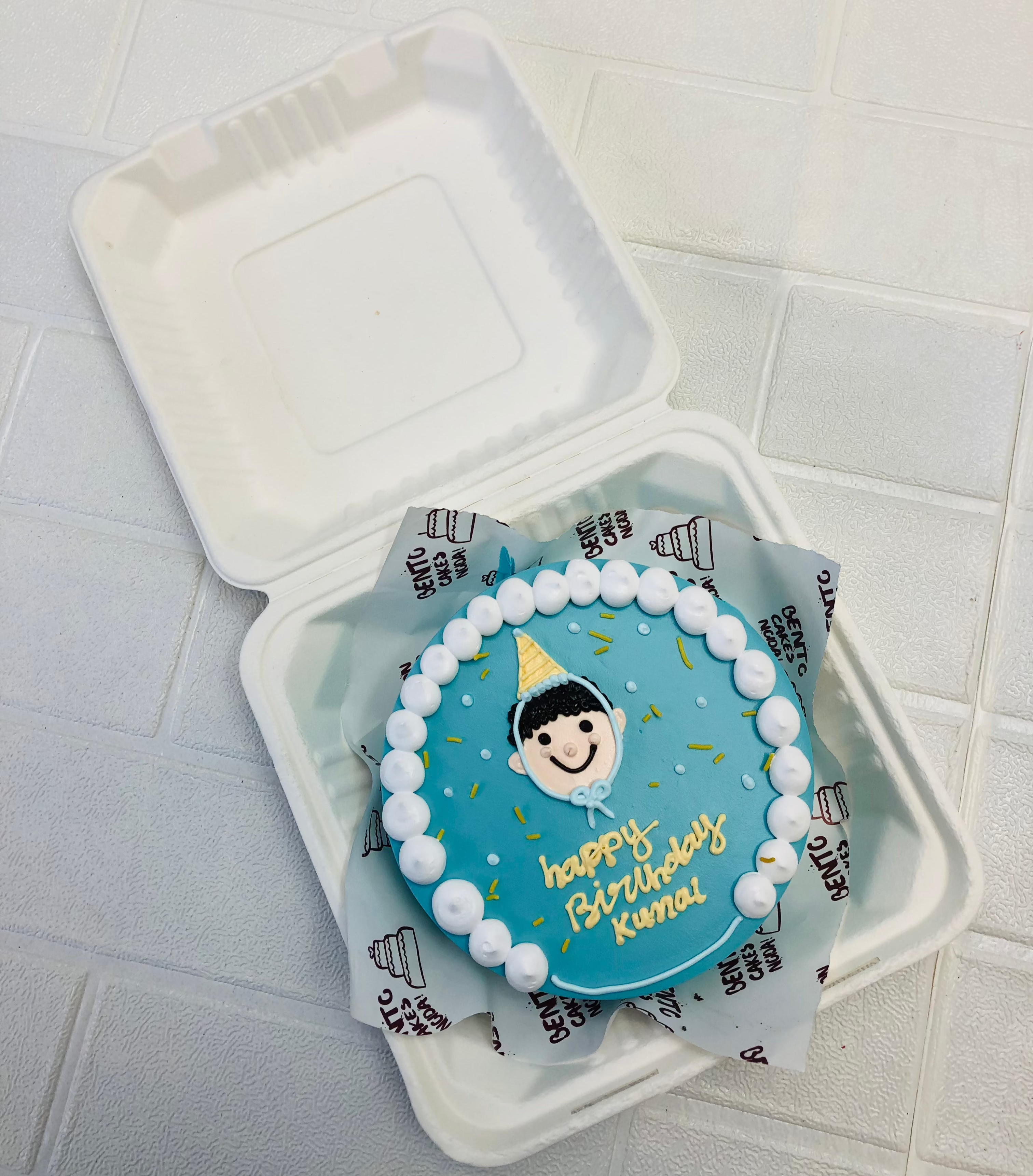 A blue bento cake with a birthday boy face.