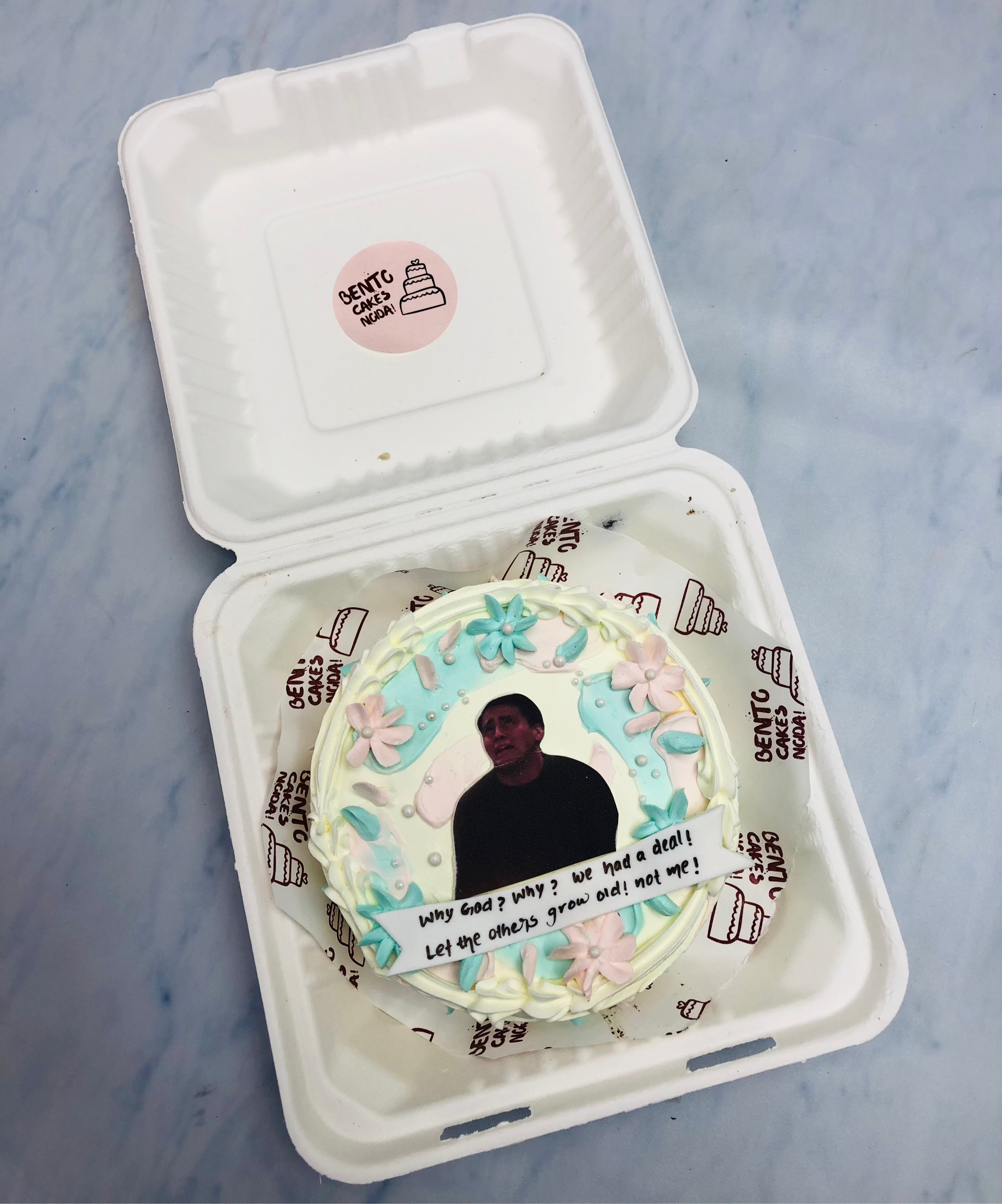 A white bento cake with floral design and a friends series image on it.