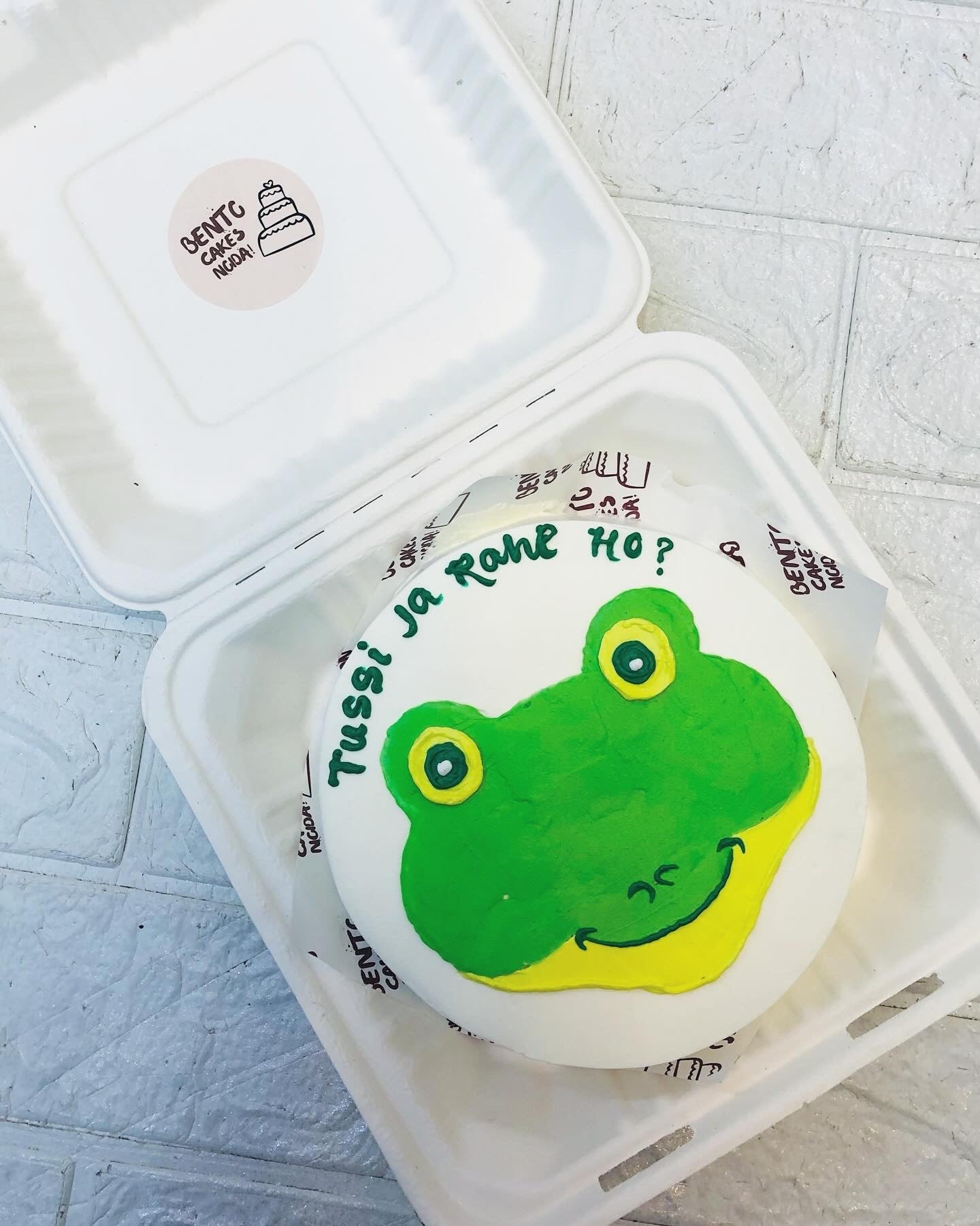 White bento cake with a frog design and  a farewell text written on it.