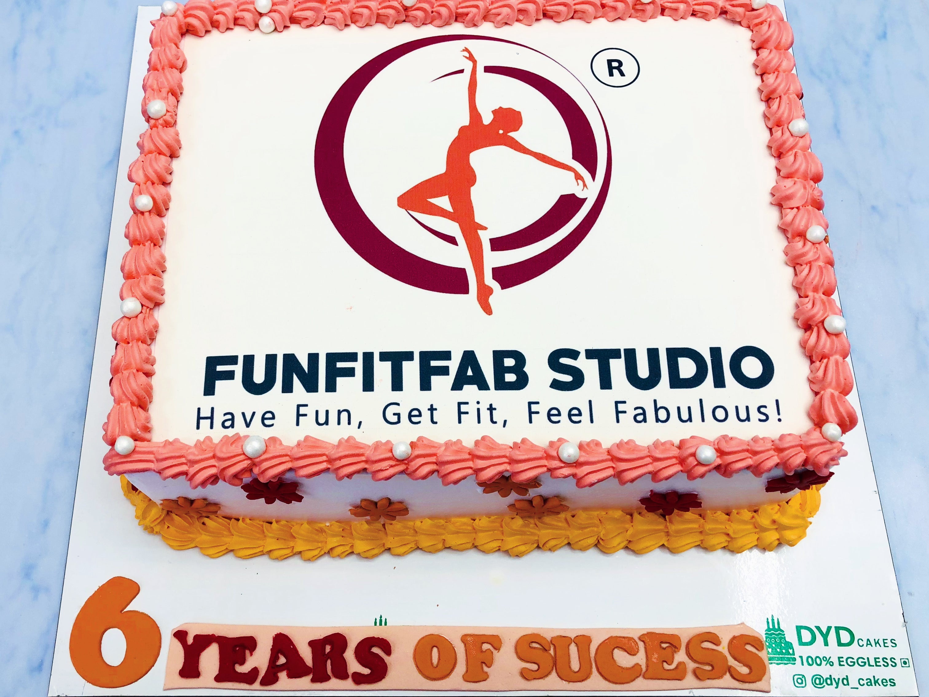 A rectangular cake commemorating FunFitFab Studio’s 6-year milestone, featuring the studio’s logo, tagline, and celebratory message, decorated with vibrant icing rosettes and elegant floral accents.