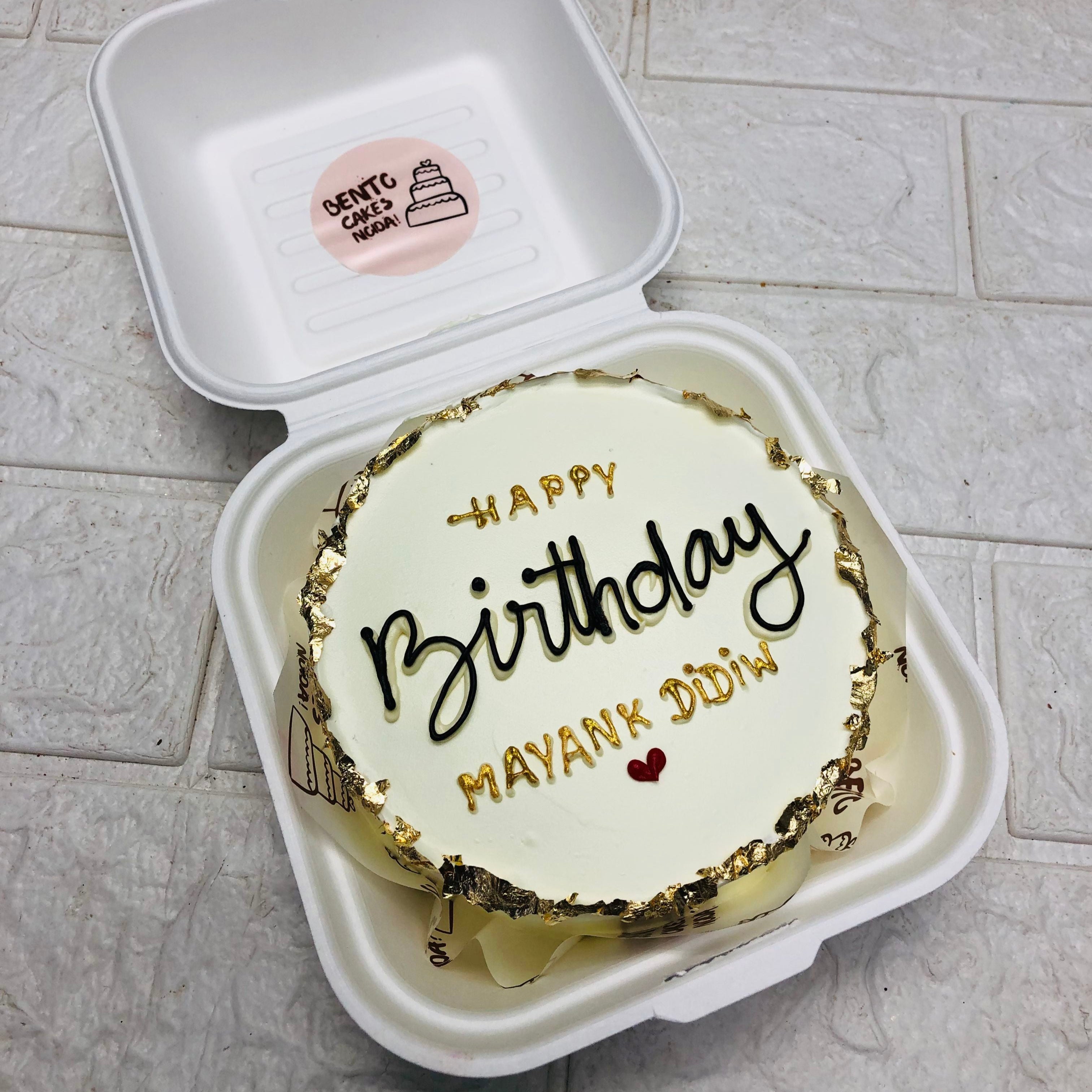 A beautifully packaged birthday cake in a mini bento box featuring a vibrant "Happy Birthday" greeting, perfect for a festive occasion.