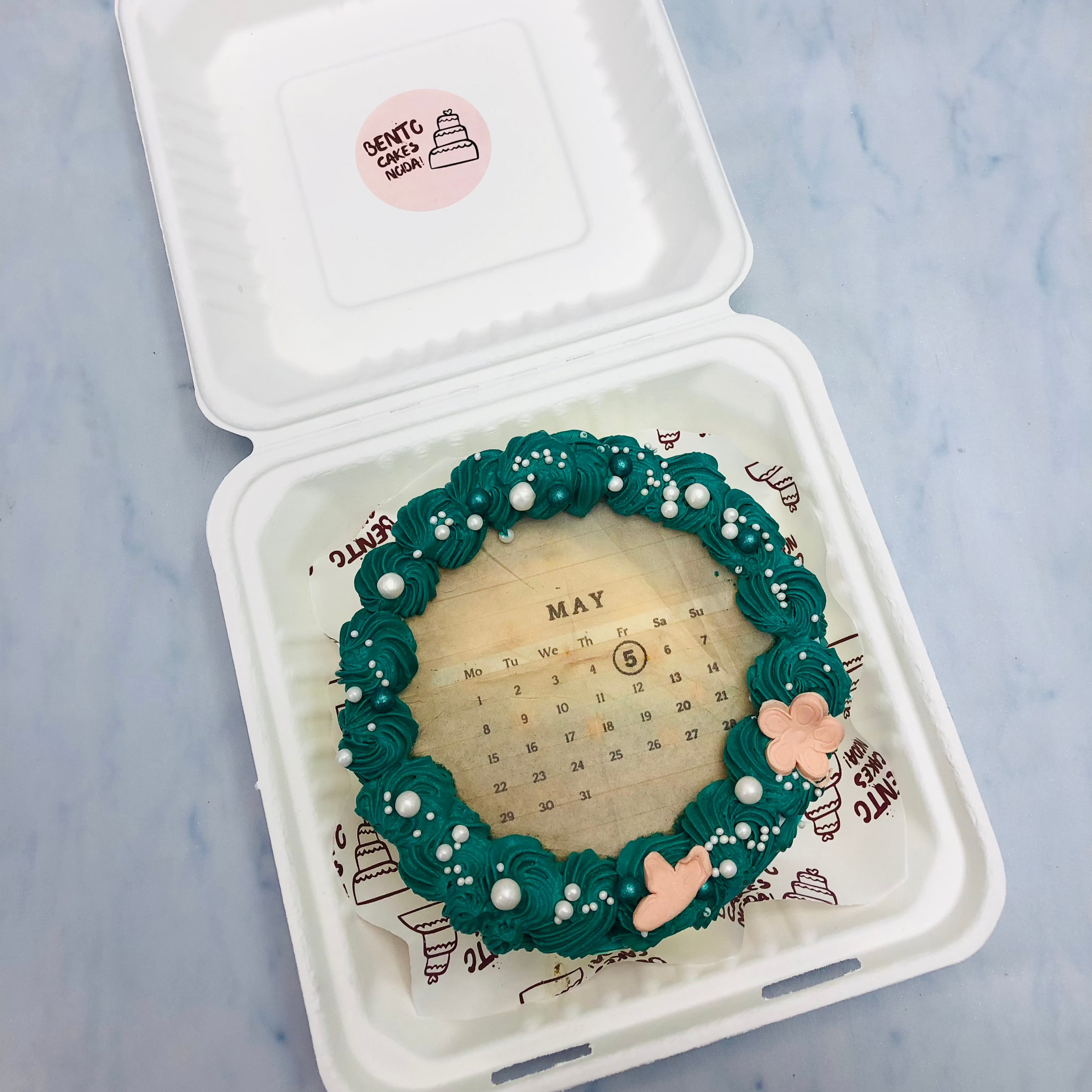 Beautifully designed fire cake in a bento box decorated with green florals.