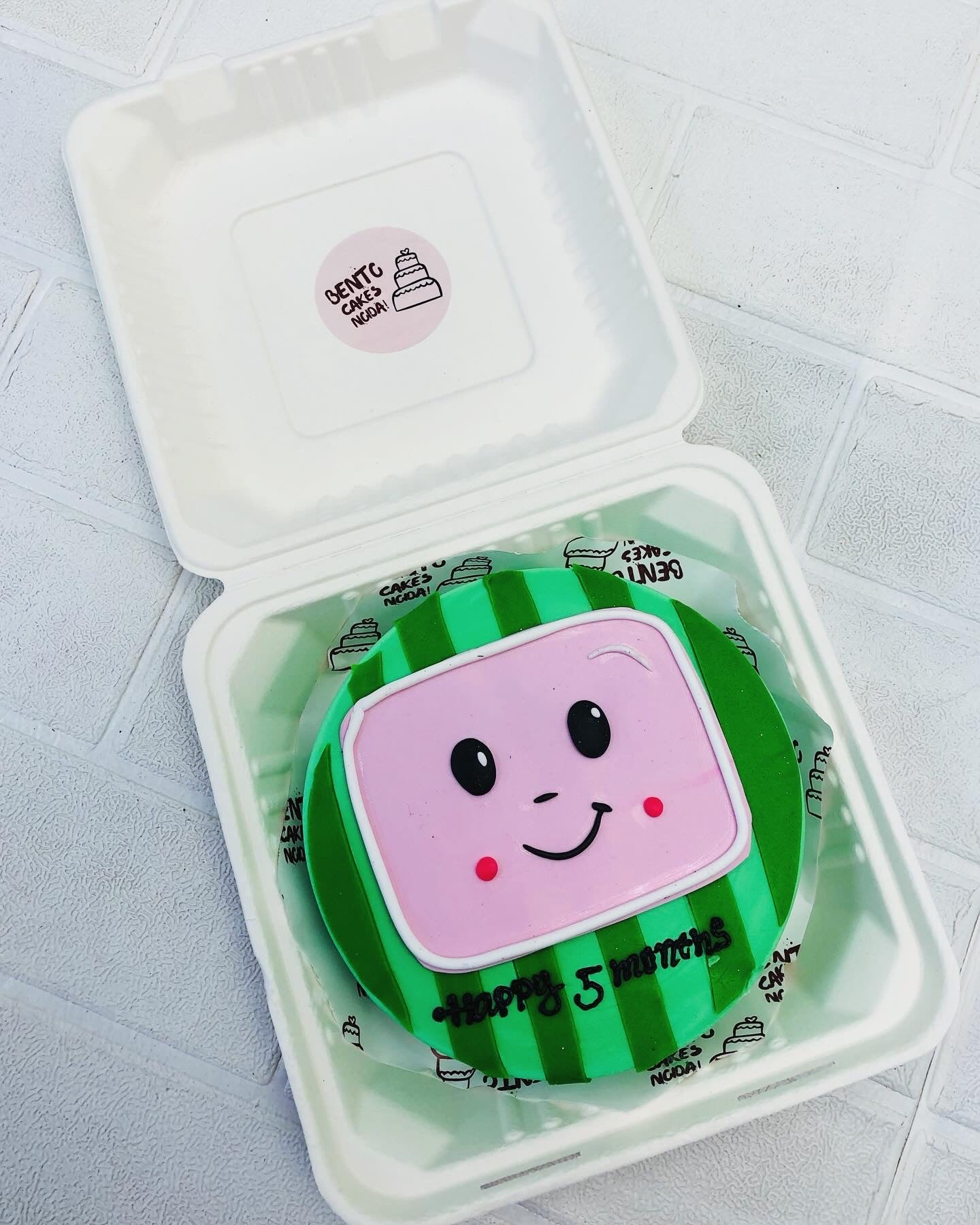 A coco melon cartoon theme bento cake in green color with cocomelon face.