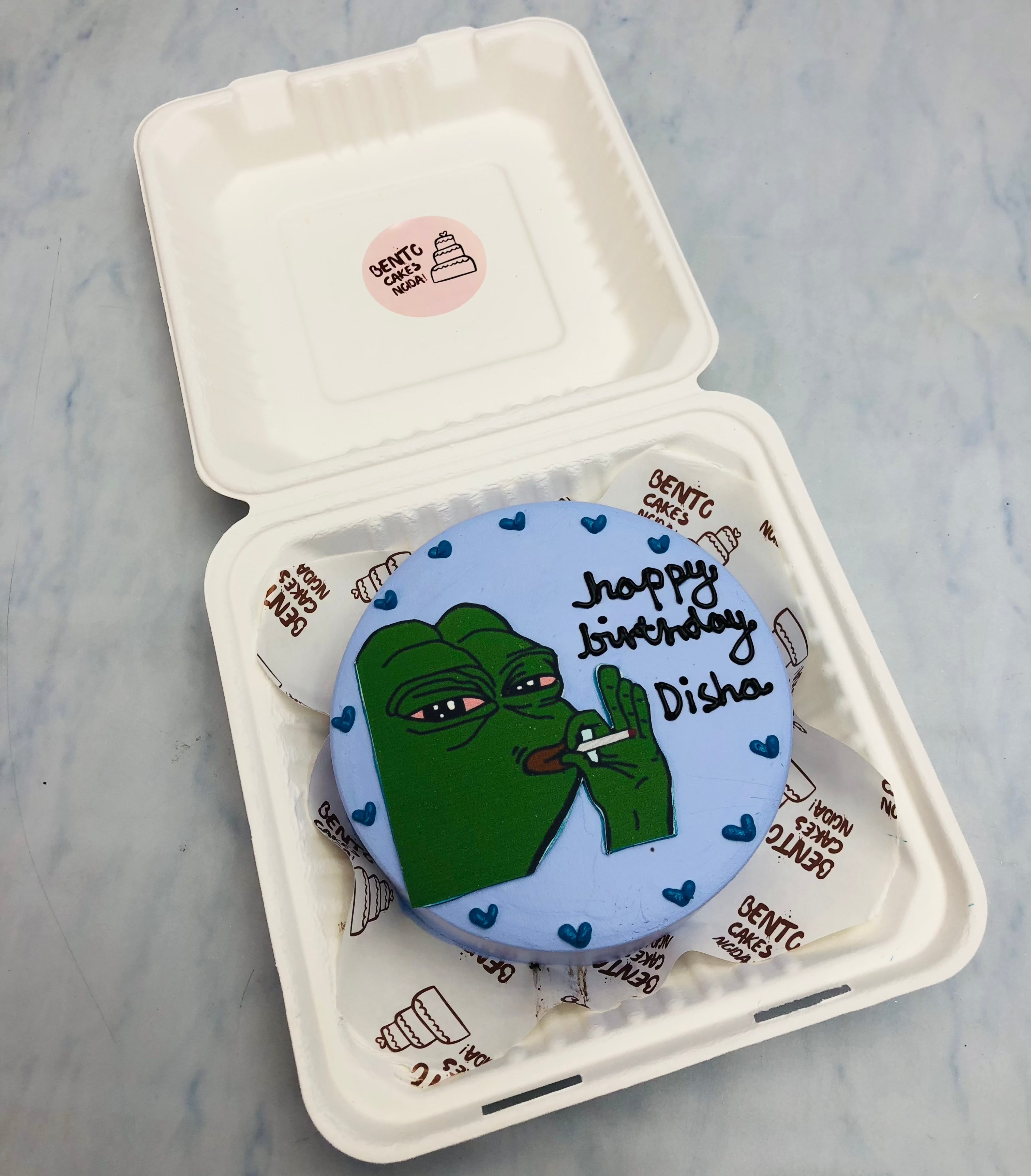 A blue bento cake is designed for a birthday girl with a smoker cartoon print on it.