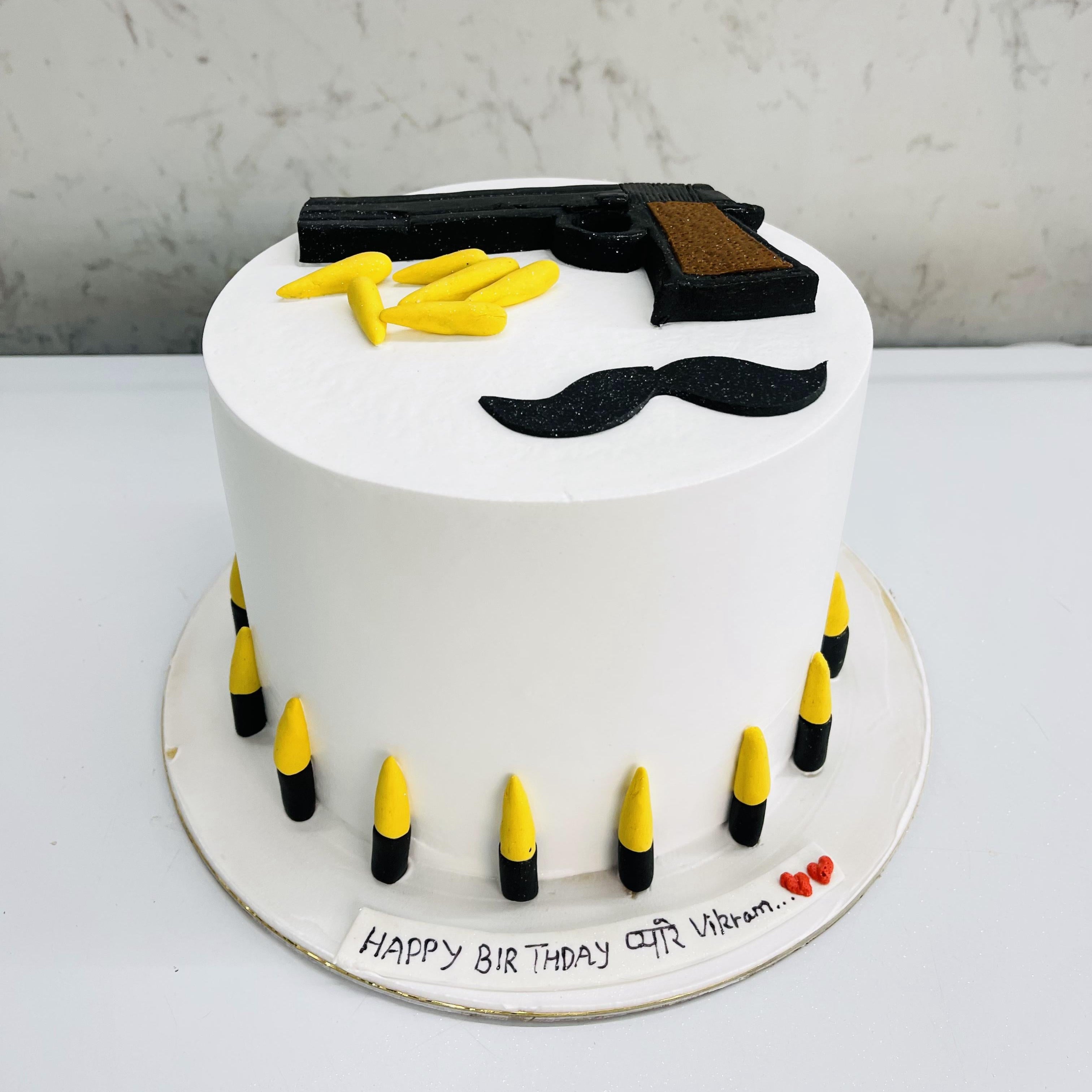 Beautifully designed white cake with a gun design on the top of cake and bullets are surrounded around it.