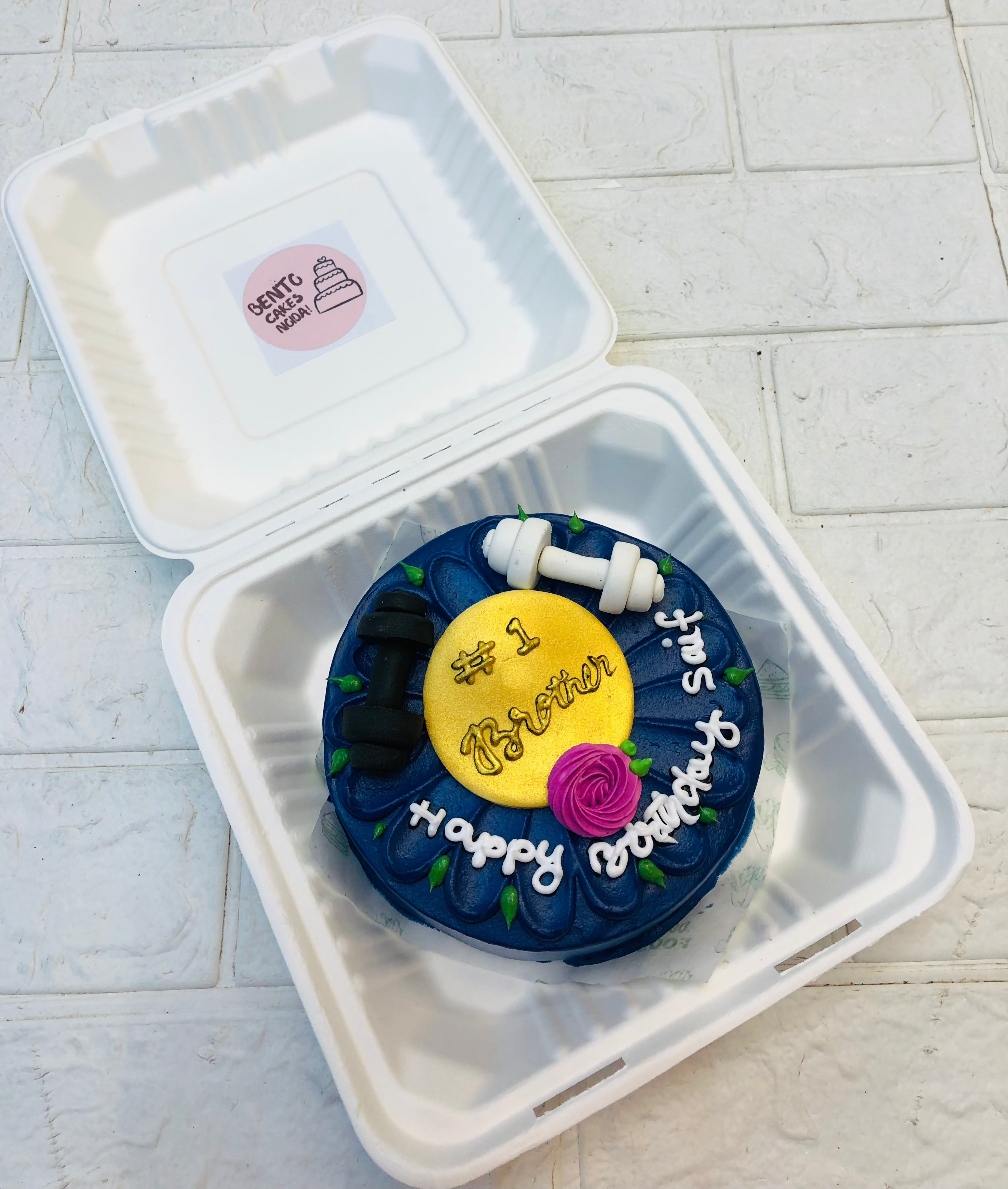A dark blue color pink floral design bento cake with fondant gym dumble.
