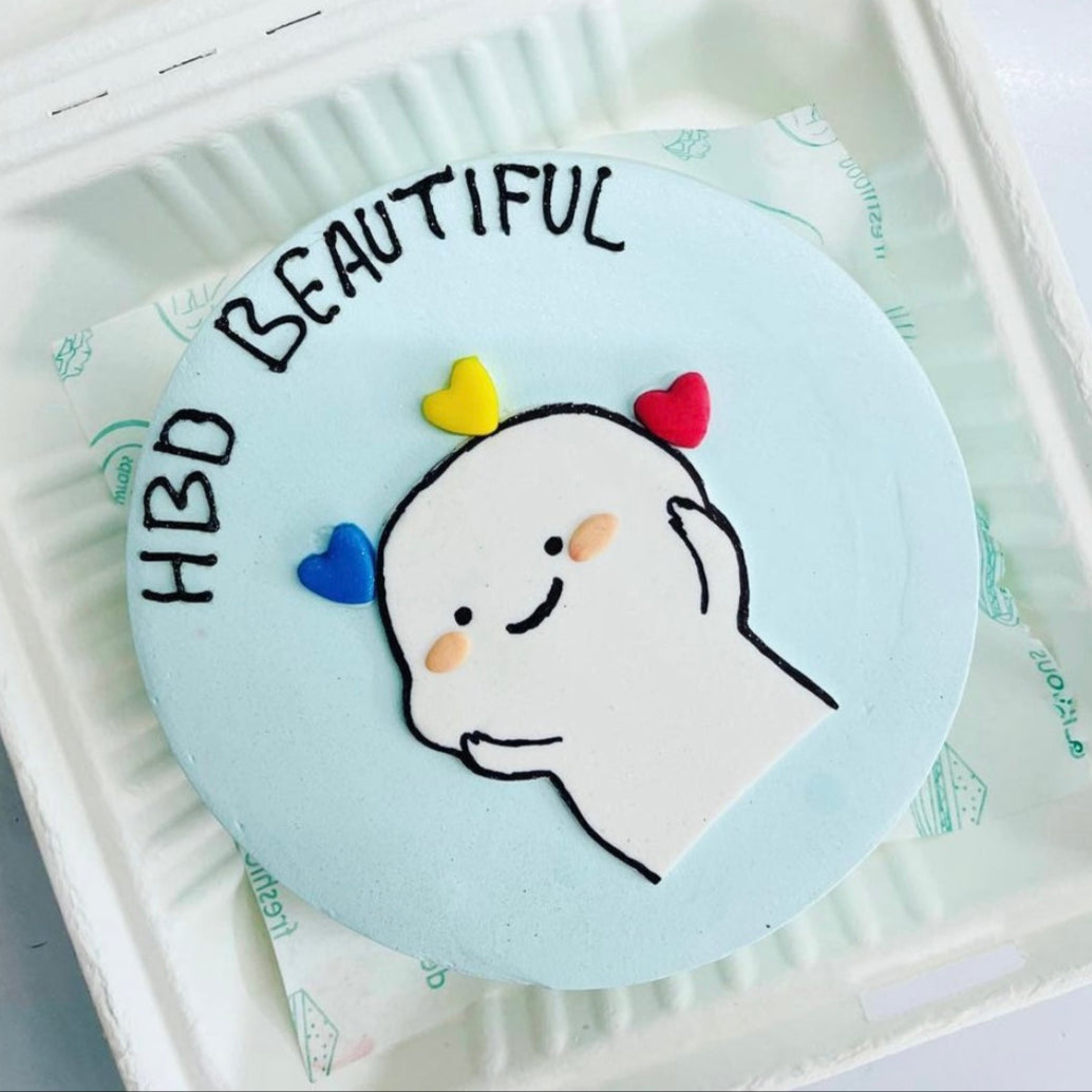 A delightful cake inside a bento box, showcasing the message "HBD Beautiful" in lovely script on its frosting with a Cute Cartoon Character.