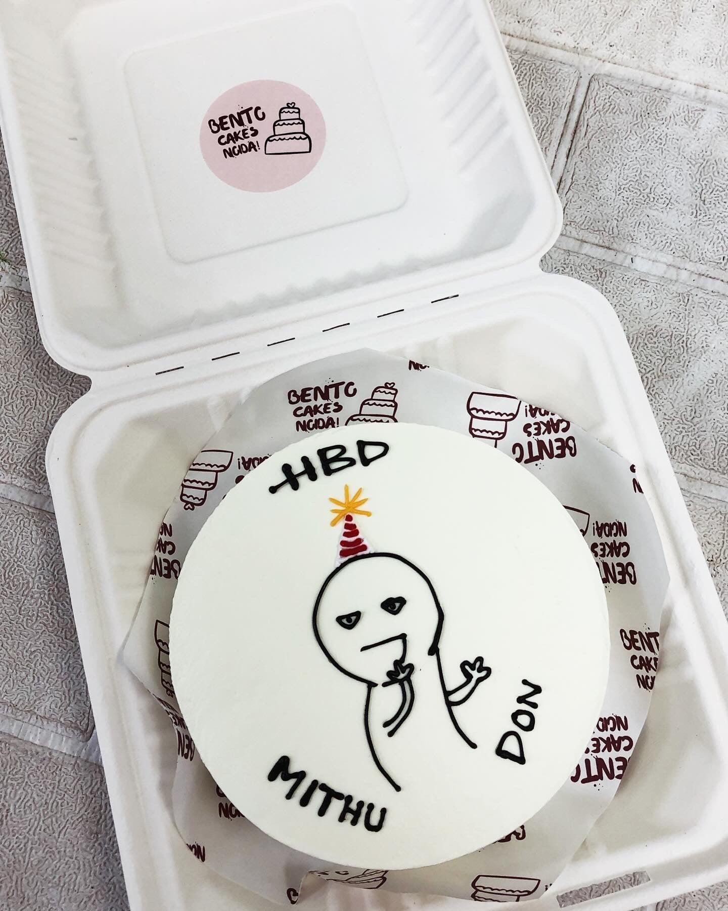 A white cartoon birthday design on white bento cake.