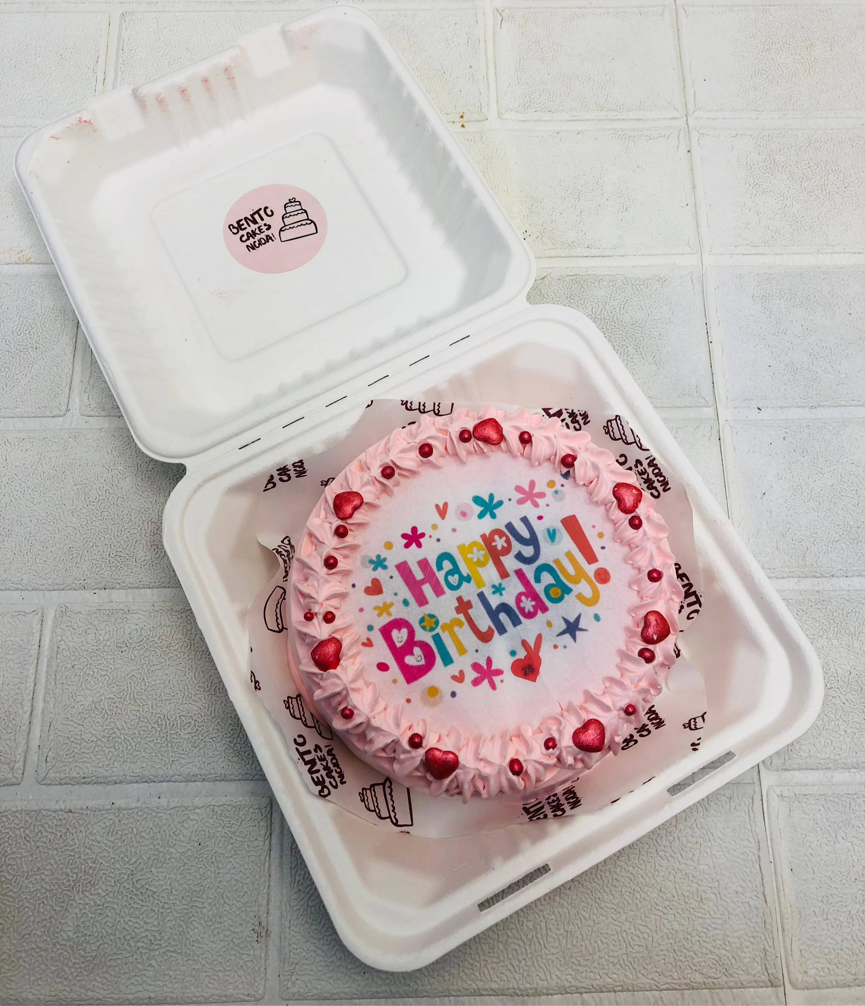 A light yellow color fire bento cake with light pink truffle design and happy birthday fire paper.