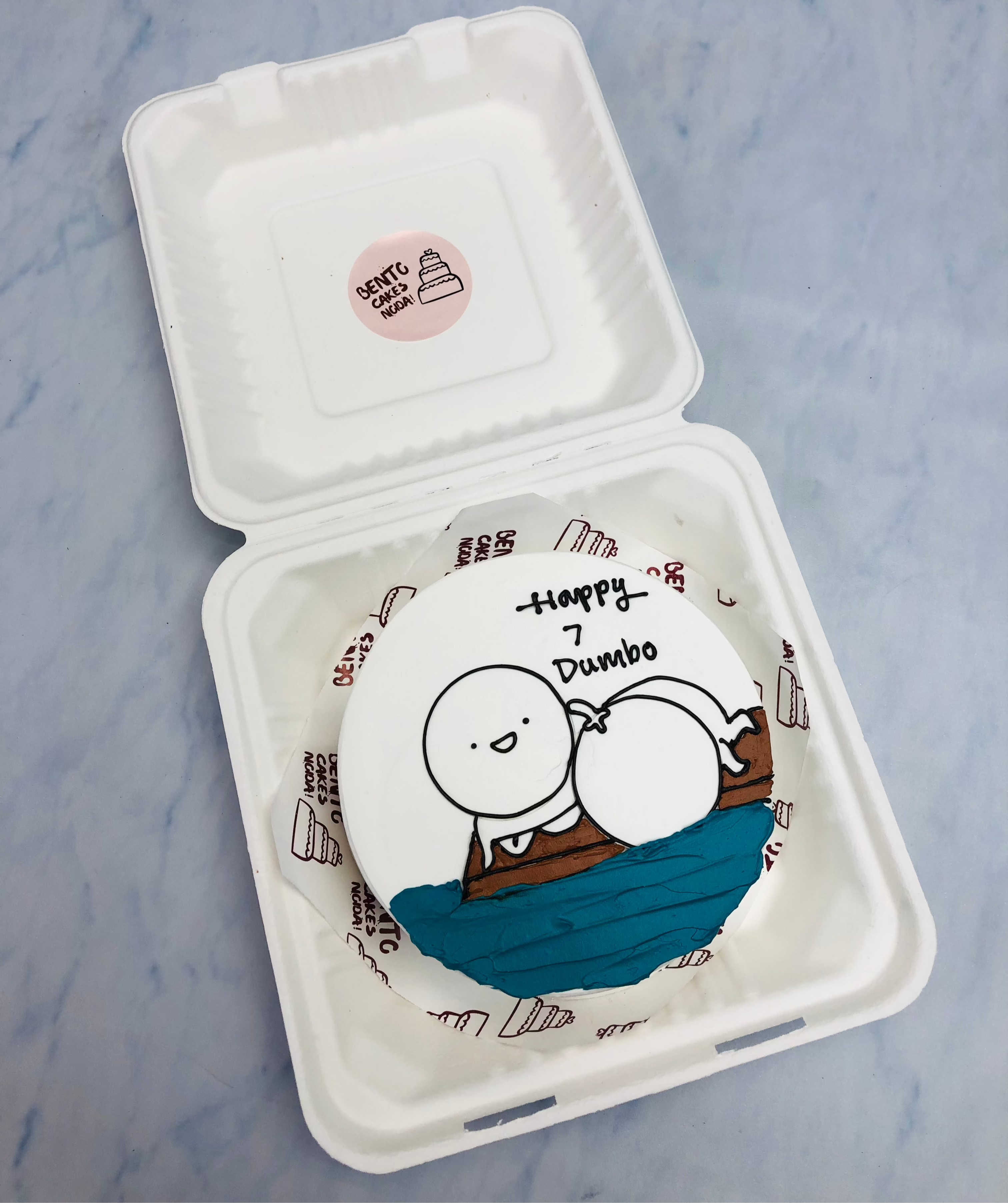 A white bento cake having a cartoon sleeping on beach side.