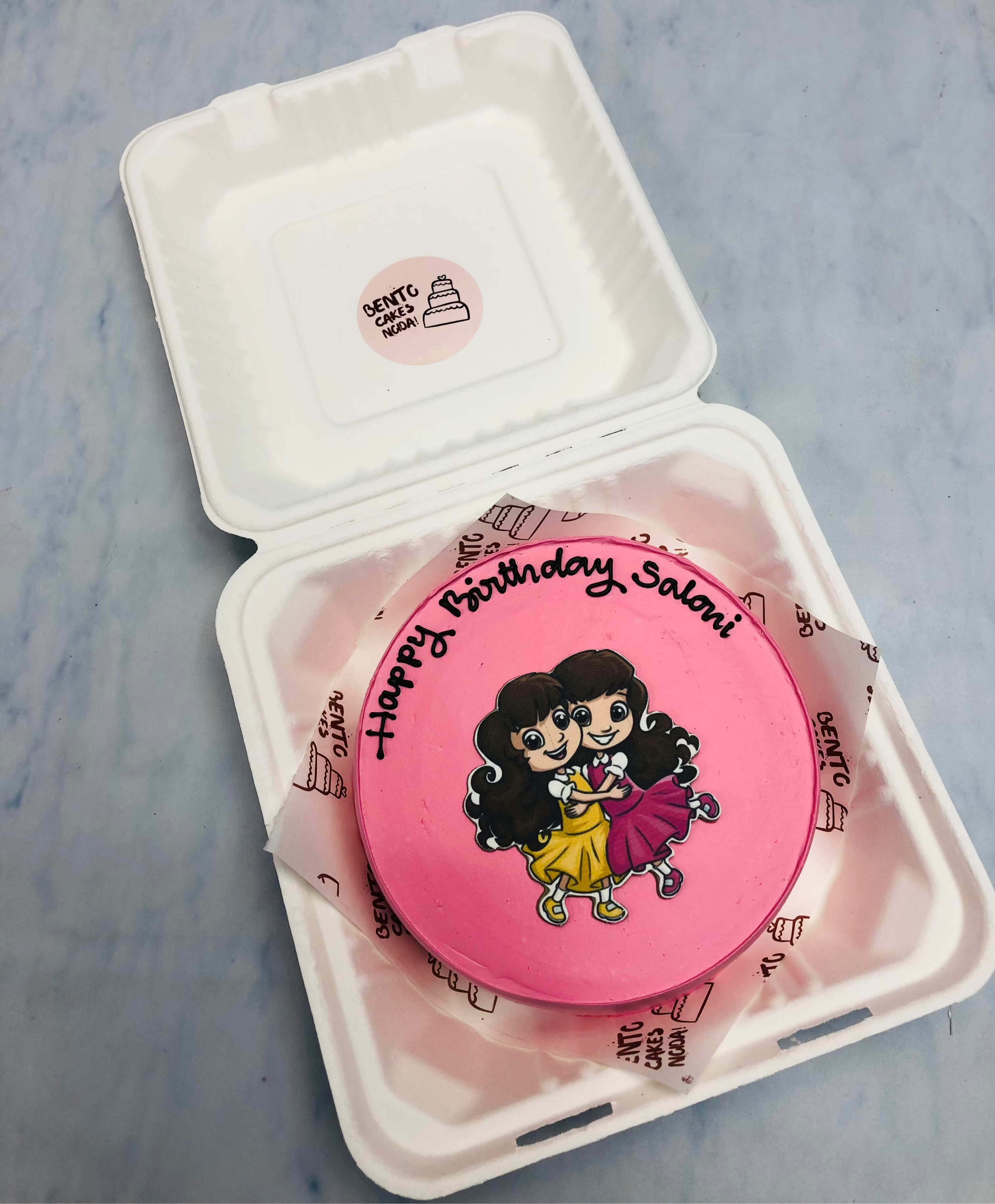 Pretty pink cake having 2 cute friends huging each other.