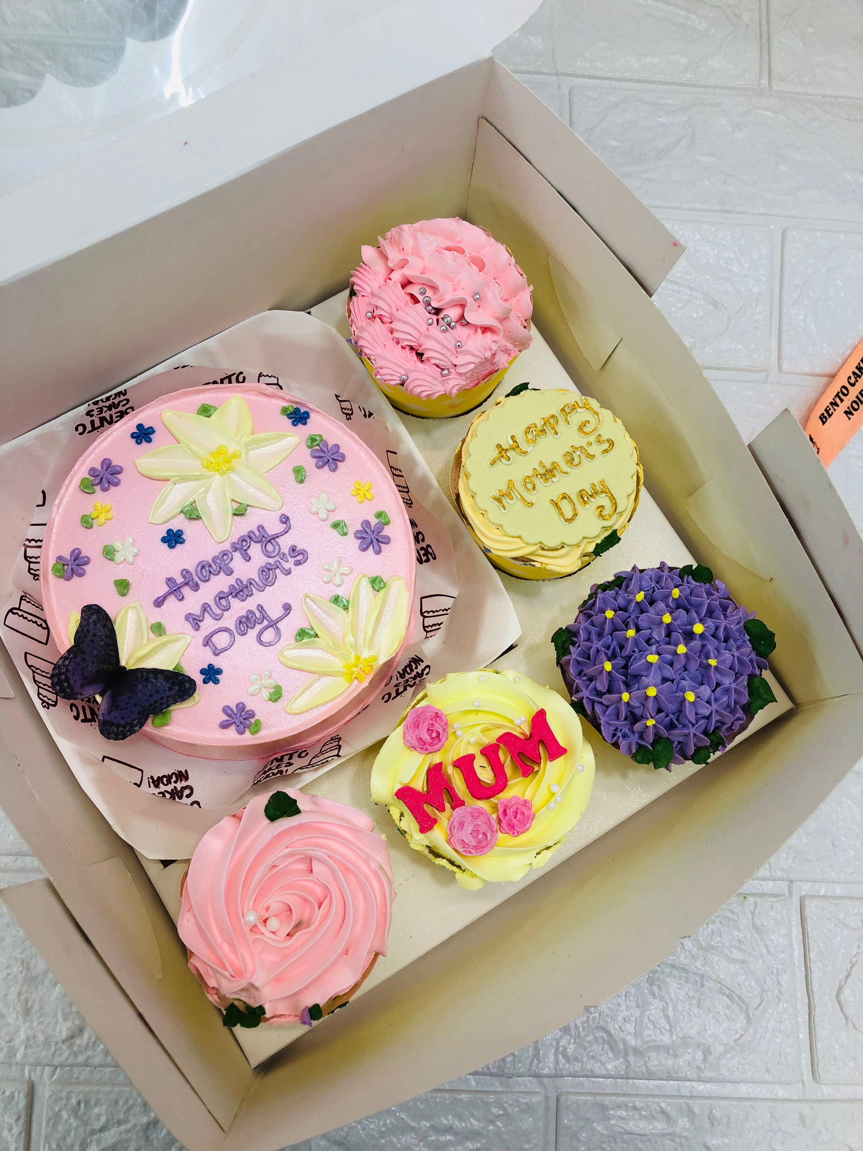 A larg bento box containing 1 cake and 5 cupcakes with different designs and colors for Mothers Day Occasion.