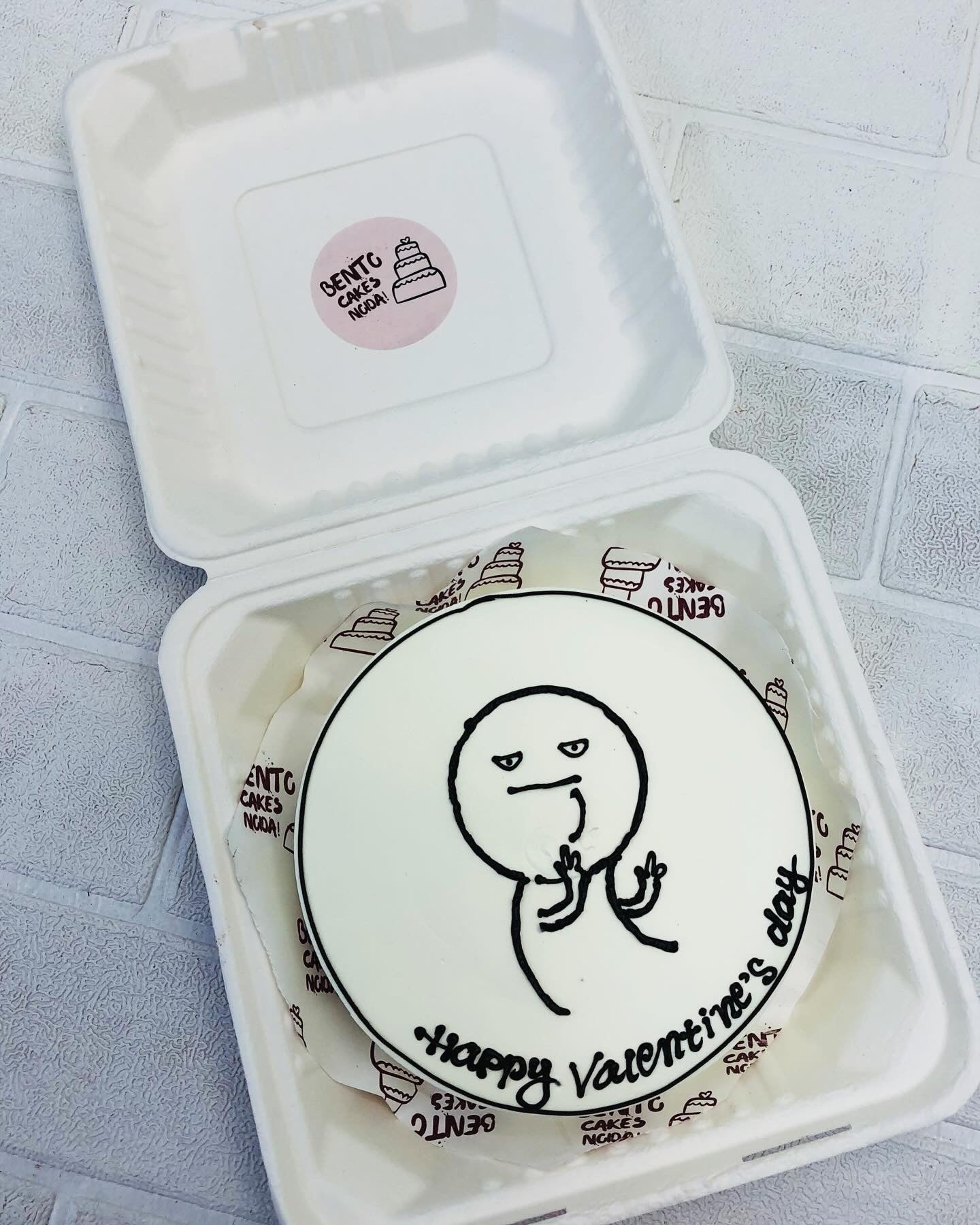 A white bento cake is designed for Vallentines Day occasion with a cartoon sketch on cake.